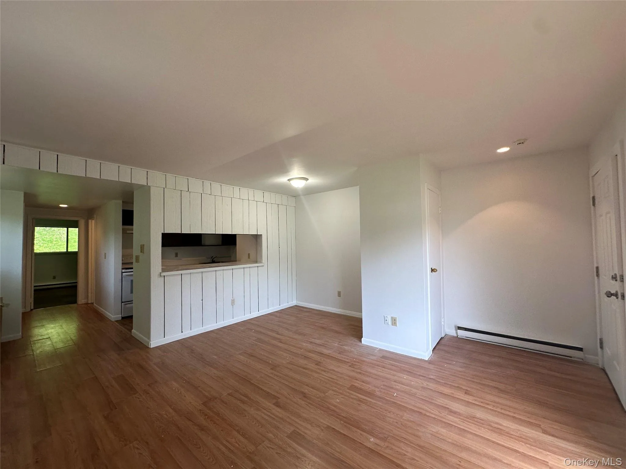 Unfurnished living room with a baseboard heating unit, wood finished floors, baseboards, and recessed lighting Unfurnished living room with a baseboard heating unit, wood finished floors, baseboards, and recessed lighting