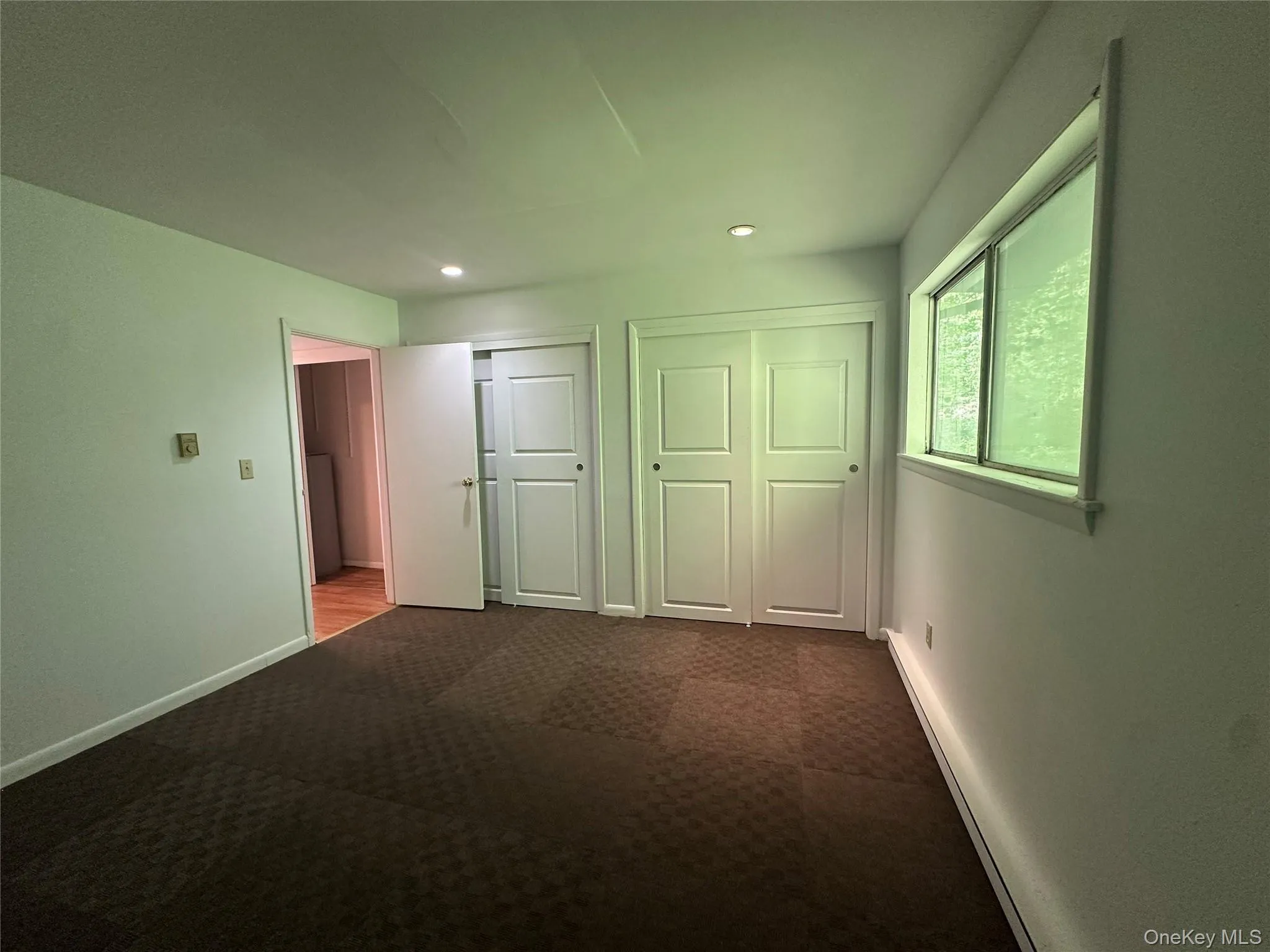 Unfurnished bedroom featuring dark colored carpet, two closets, recessed lighting, and baseboards Unfurnished bedroom featuring dark colored carpet, two closets, recessed lighting, and baseboards