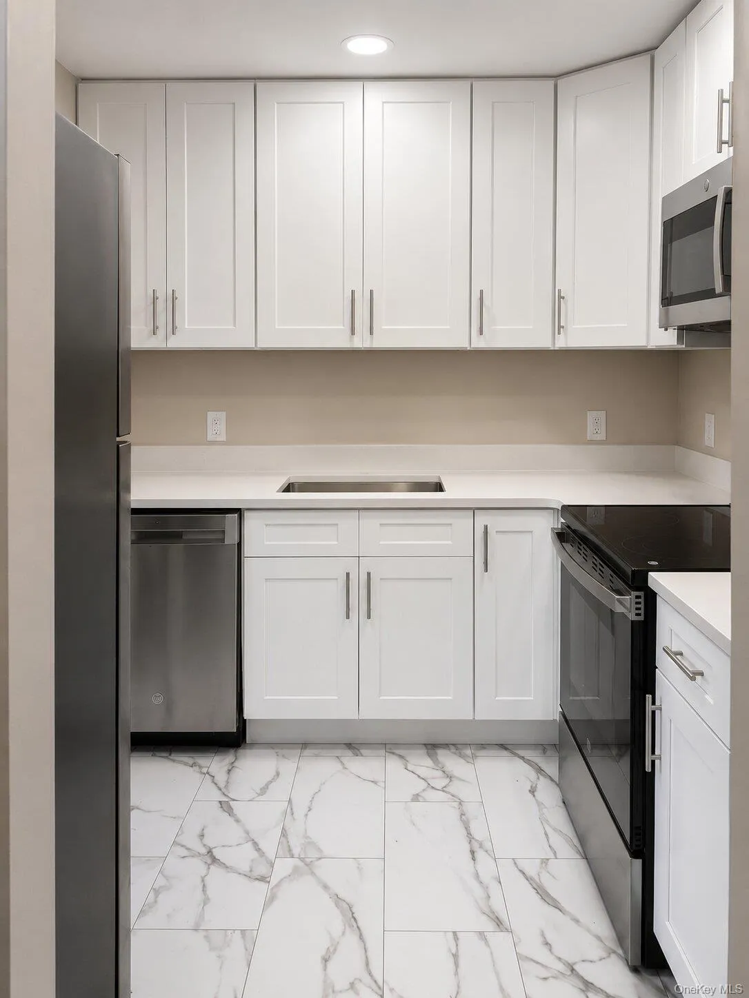 Updated Kitchen – Beautifully renovated kitchen featuring white cabinetry, quartz-style countertops, stainless-steel appliances, recessed lighting, and elegant tile flooring. Updated Kitchen – Beautifully renovated kitchen featuring white cabinetry, quartz-style countertops, stainless-steel appliances, recessed lighting, and elegant tile flooring.
