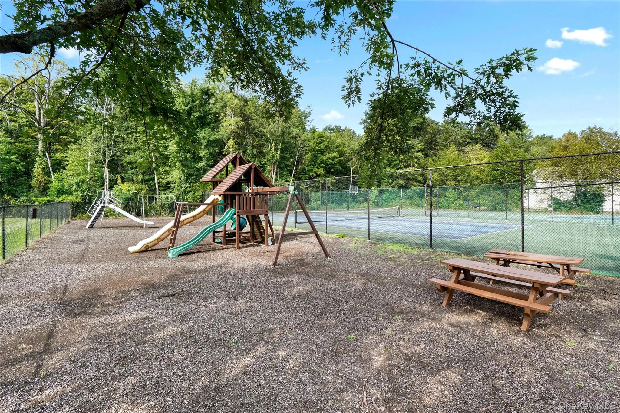 Community Playground – A dedicated children’s play area featuring slides, swings, climbing structures, picnic tables, and a soft ground surface. Community Playground – A dedicated children’s play area featuring slides, swings, climbing structures, picnic tables, and a soft ground surface.