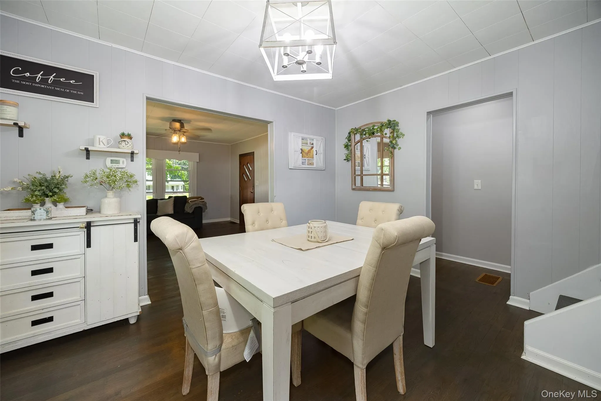 Dining area featuring dark wood-finish flooring and light gray paneling Dining area featuring dark wood-finish flooring and light gray paneling