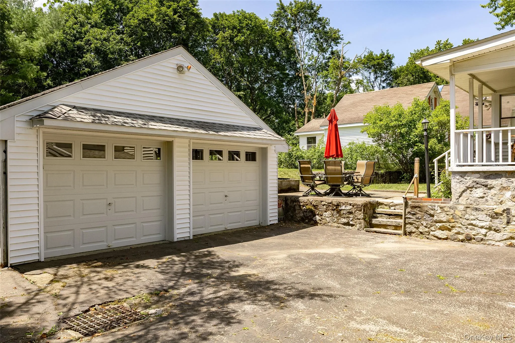 Two-car garage with white paneled doors and upper window inserts, featuring white siding and an asphalt shingle roof Two-car garage with white paneled doors and upper window inserts, featuring white siding and an asphalt shingle roof