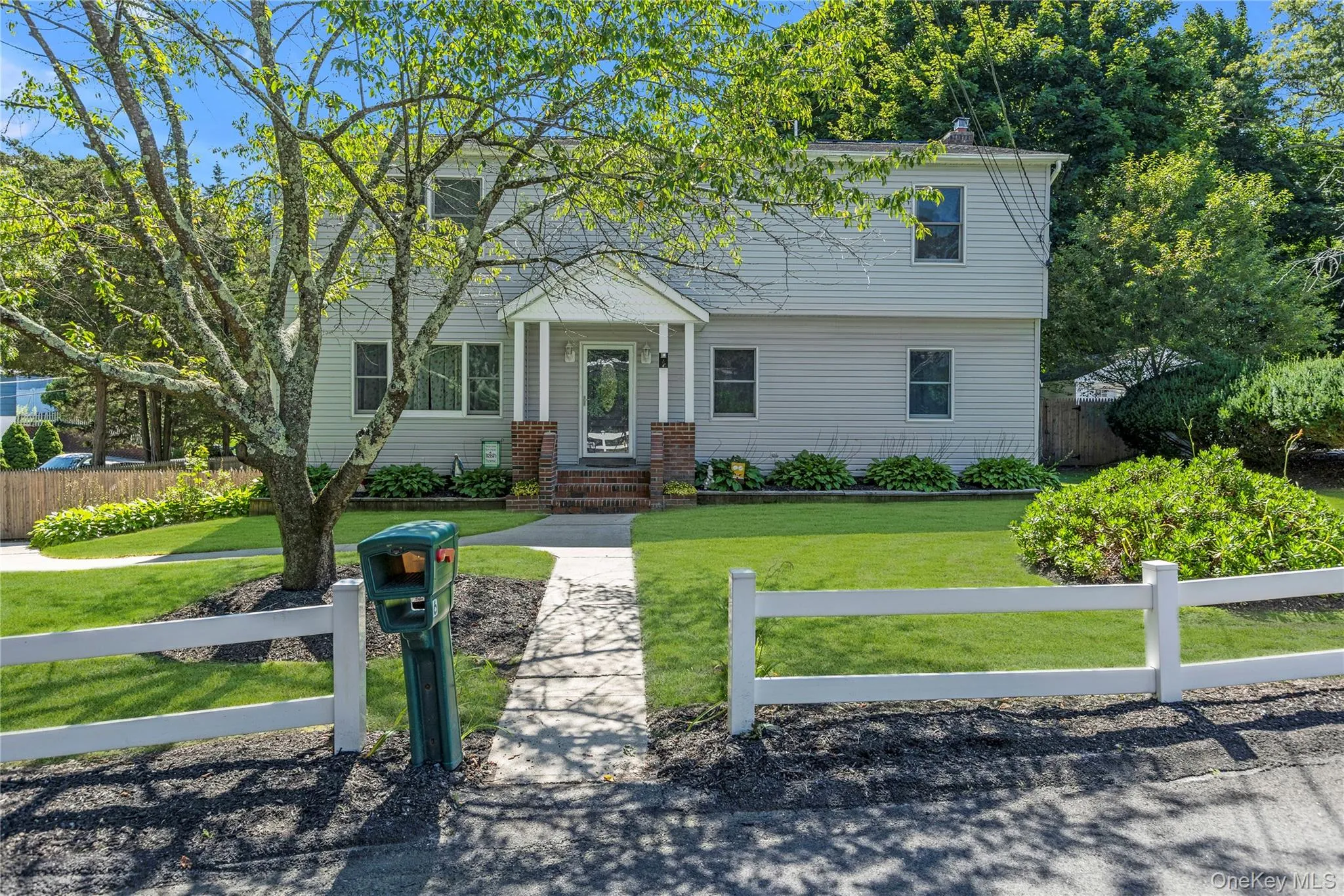Light gray siding exterior with a covered porch featuring white columns and brick accents Light gray siding exterior with a covered porch featuring white columns and brick accents