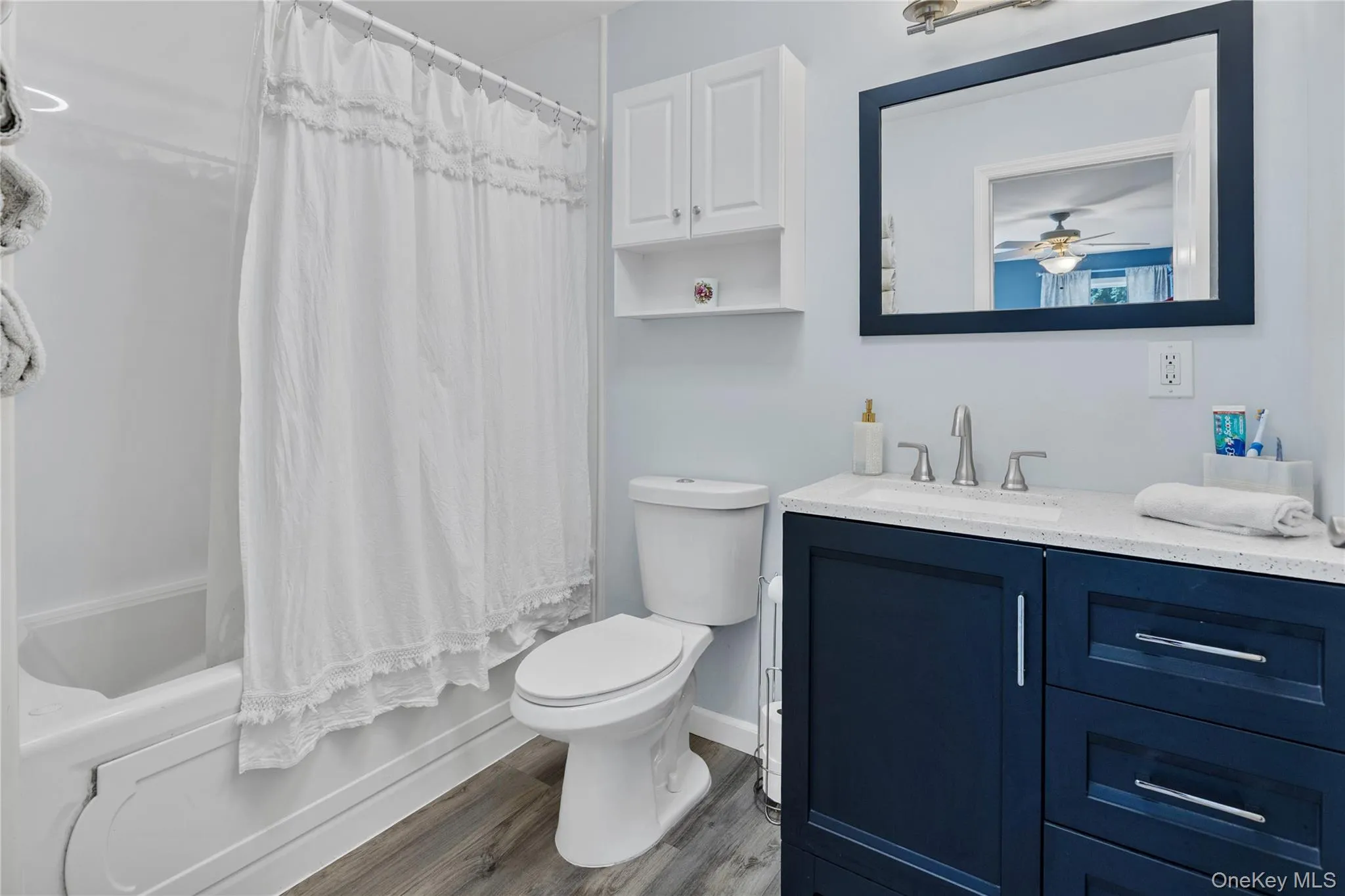 Bathroom featuring a dark blue vanity with a light-colored countertop, an undermount sink, and a framed mirror Bathroom featuring a dark blue vanity with a light-colored countertop, an undermount sink, and a framed mirror