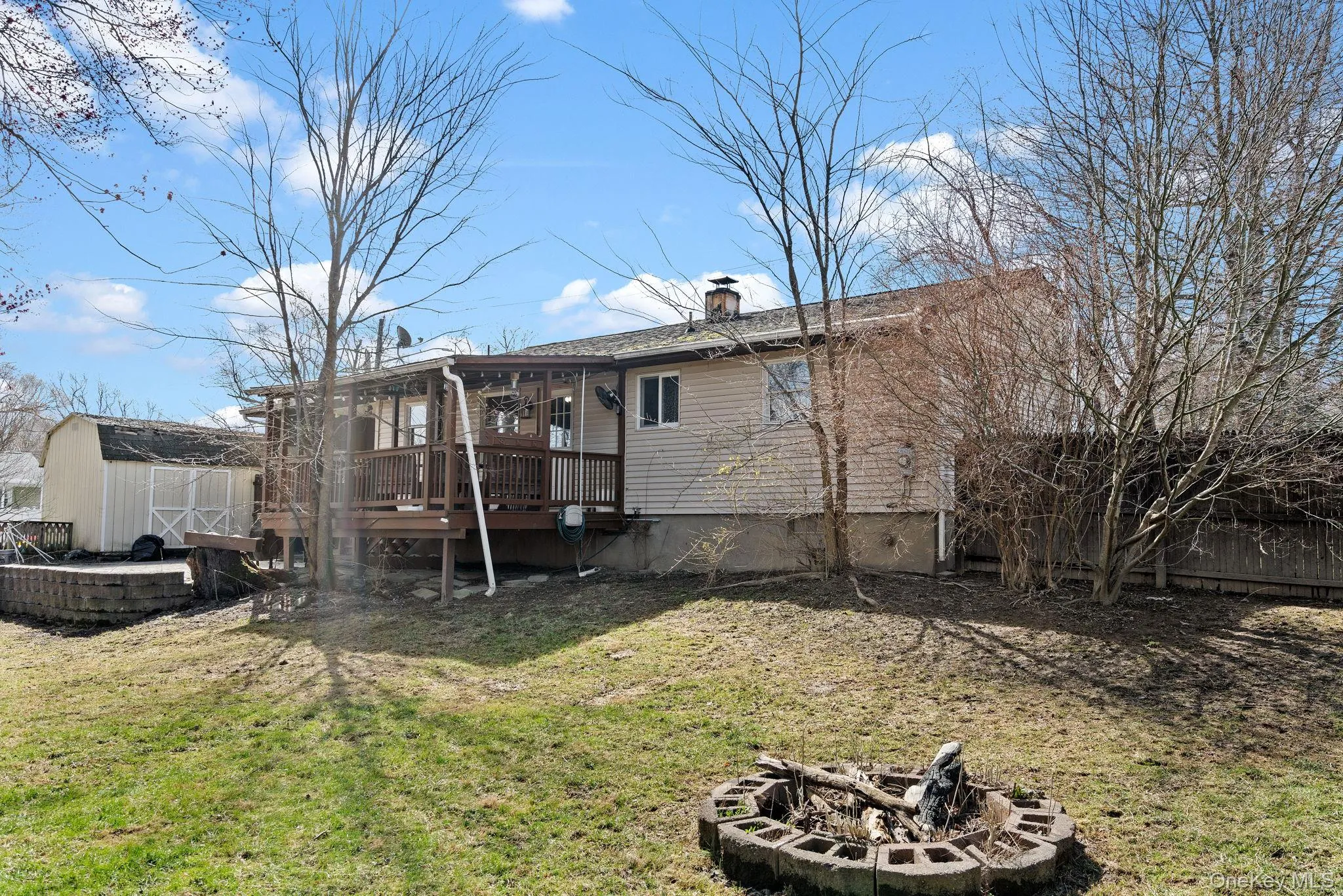 Rear view of property featuring an outbuilding, a wooden deck, a storage unit, an outdoor fire pit, and a yard Rear view of property featuring an outbuilding, a wooden deck, a storage unit, an outdoor fire pit, and a yard