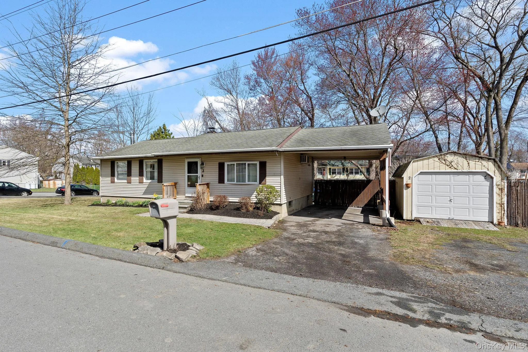 Ranch-style house featuring a front yard, roof with shingles, driveway, an outbuilding, and a carport Ranch-style house featuring a front yard, roof with shingles, driveway, an outbuilding, and a carport