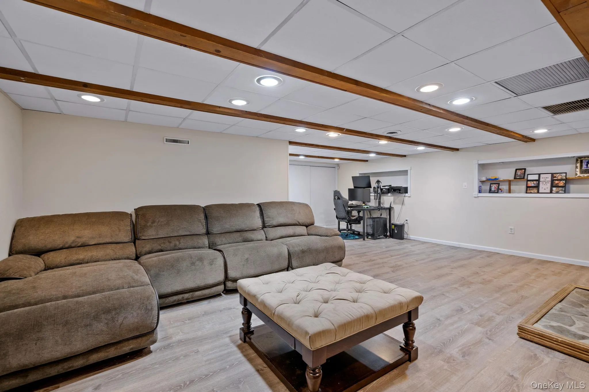Living room featuring visible vents, light wood-style floors, and a paneled ceiling Living room featuring visible vents, light wood-style floors, and a paneled ceiling
