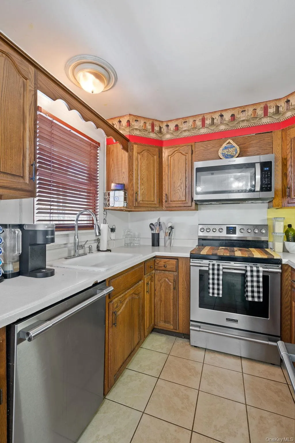 Kitchen featuring light countertops, a sink, stainless steel appliances, and light tile patterned floors Kitchen featuring light countertops, a sink, stainless steel appliances, and light tile patterned floors
