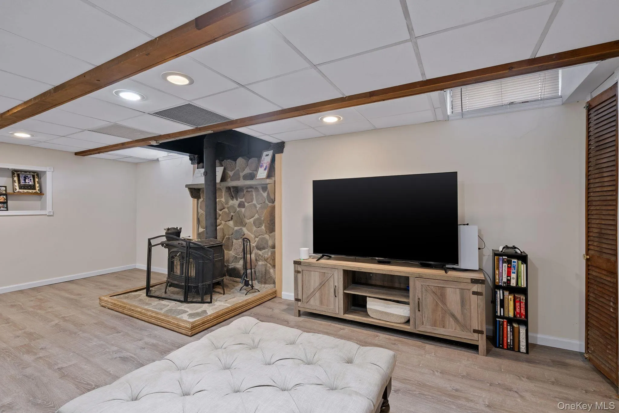 Living area featuring wood finished floors, a wood stove, baseboards, recessed lighting, and a drop ceiling Living area featuring wood finished floors, a wood stove, baseboards, recessed lighting, and a drop ceiling
