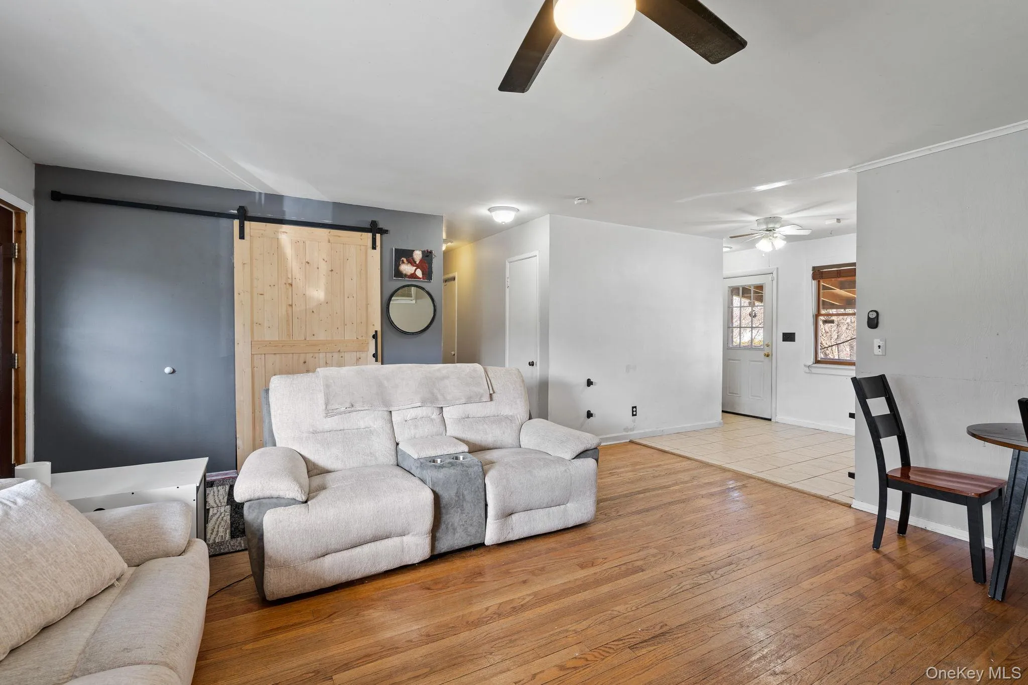 Living area featuring hardwood / wood-style floors, baseboards, a barn door, and ceiling fan Living area featuring hardwood / wood-style floors, baseboards, a barn door, and ceiling fan