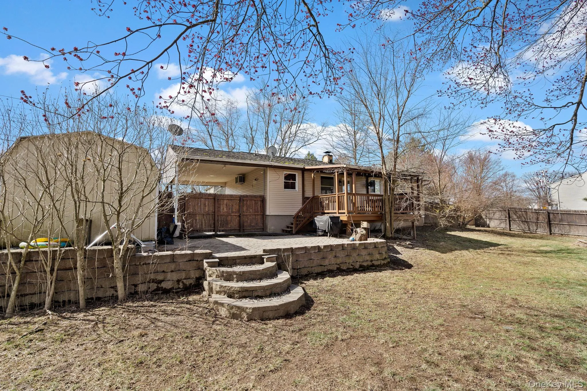 Rear view of property featuring a wooden deck, an outdoor structure, a fenced backyard, a patio, and a yard Rear view of property featuring a wooden deck, an outdoor structure, a fenced backyard, a patio, and a yard