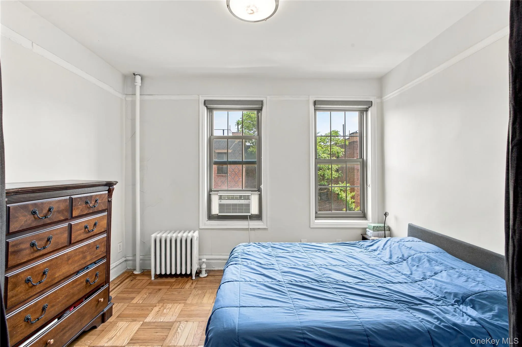2nd Bedroom featuring two casement windows with roller shades, wood-finish parquet flooring, and a ceiling-mounted light fixture 2nd Bedroom featuring two casement windows with roller shades, wood-finish parquet flooring, and a ceiling-mounted light fixture