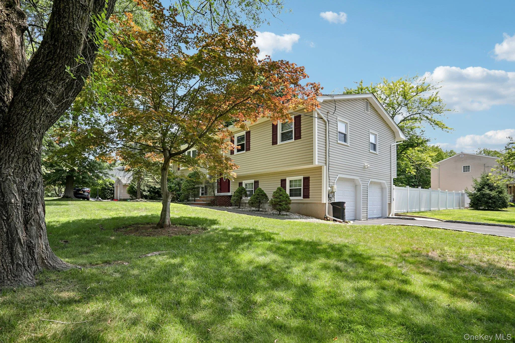 Split-level home featuring light-colored siding and a two-car garage Split-level home featuring light-colored siding and a two-car garage
