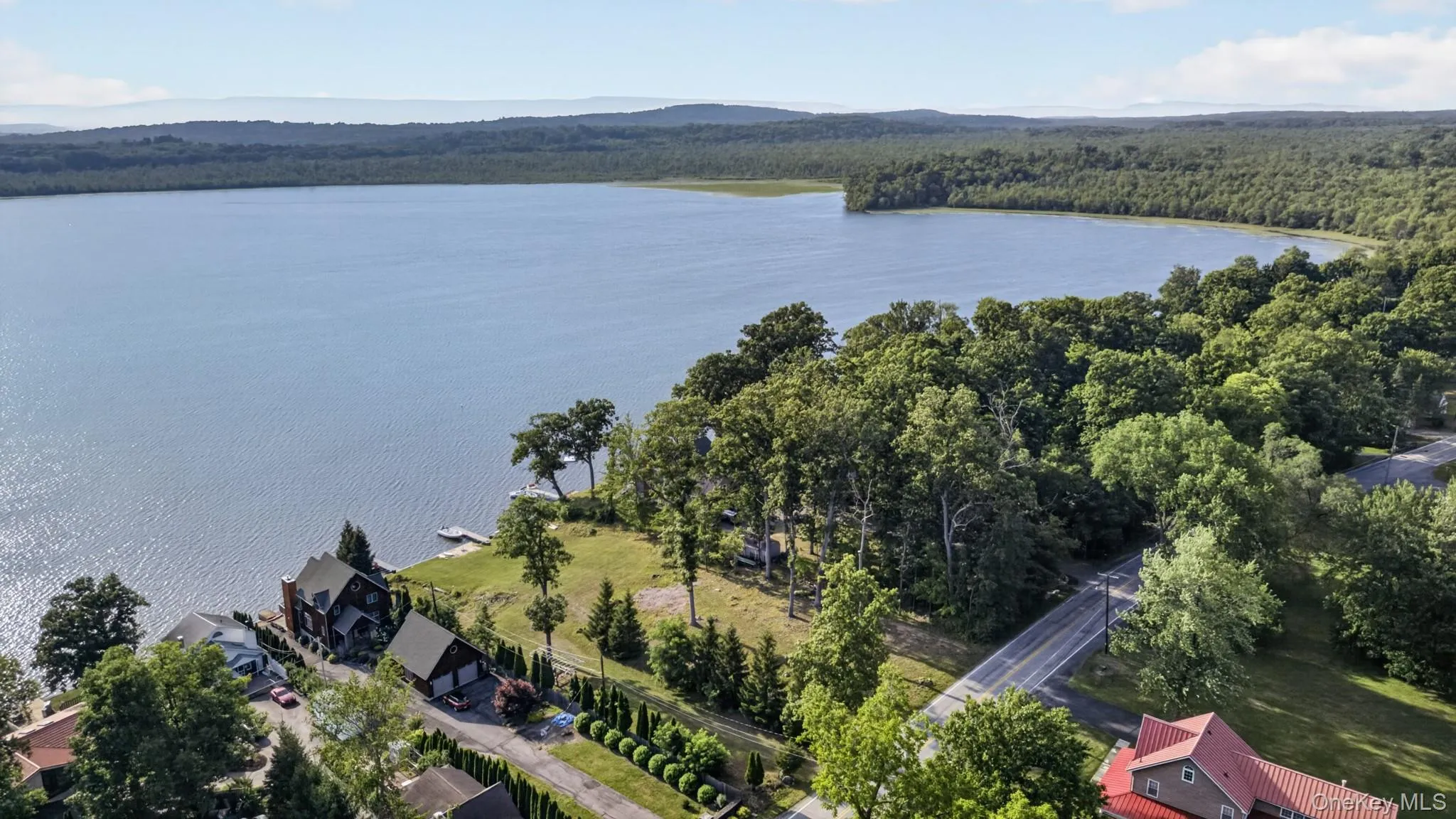 Expansive waterfront setting featuring a large body of water, dense tree lines, and a distant mountain range Expansive waterfront setting featuring a large body of water, dense tree lines, and a distant mountain range