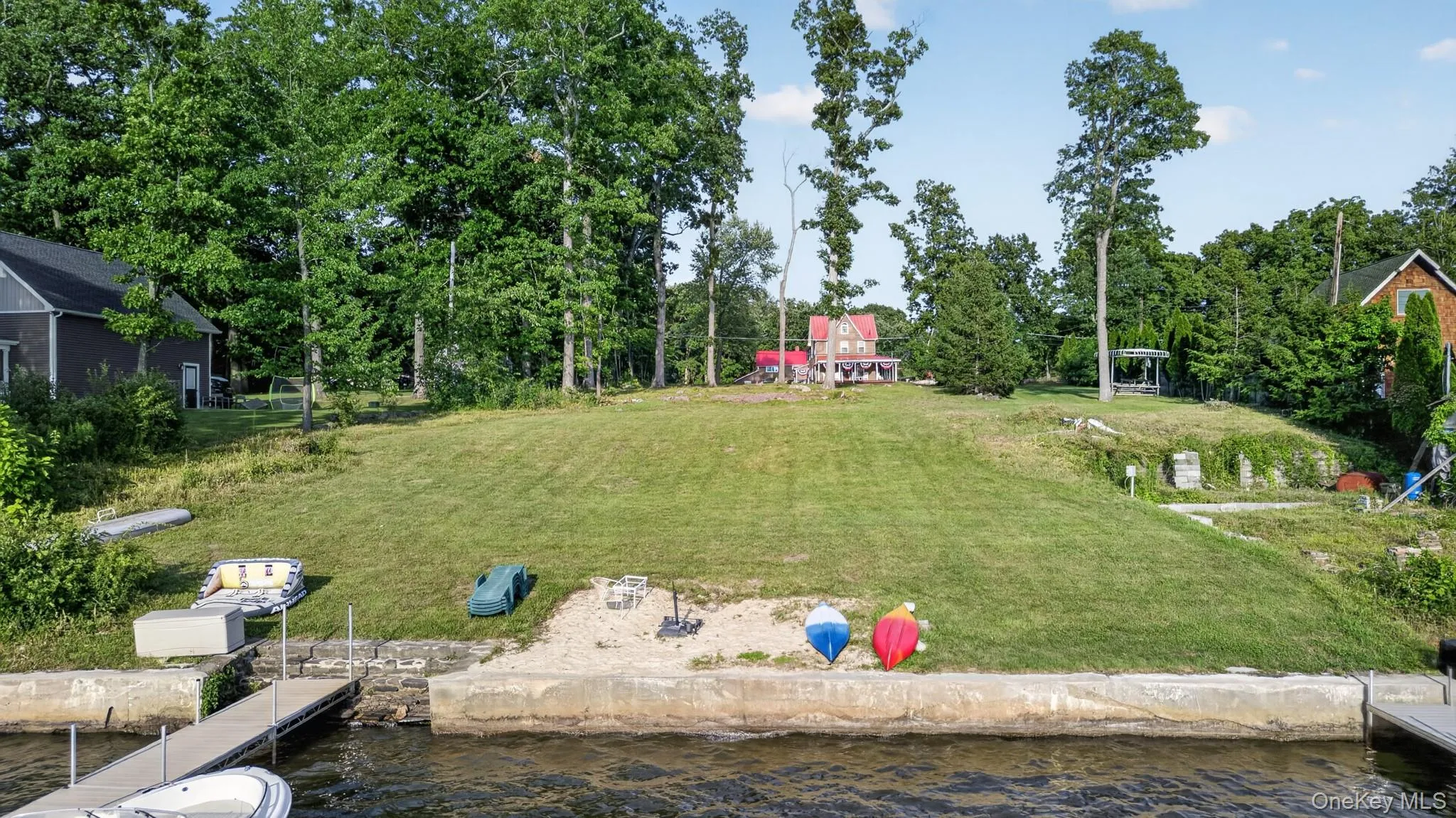 Waterfront property featuring a private dock, concrete retaining wall, and a sloped, grassy lawn Waterfront property featuring a private dock, concrete retaining wall, and a sloped, grassy lawn