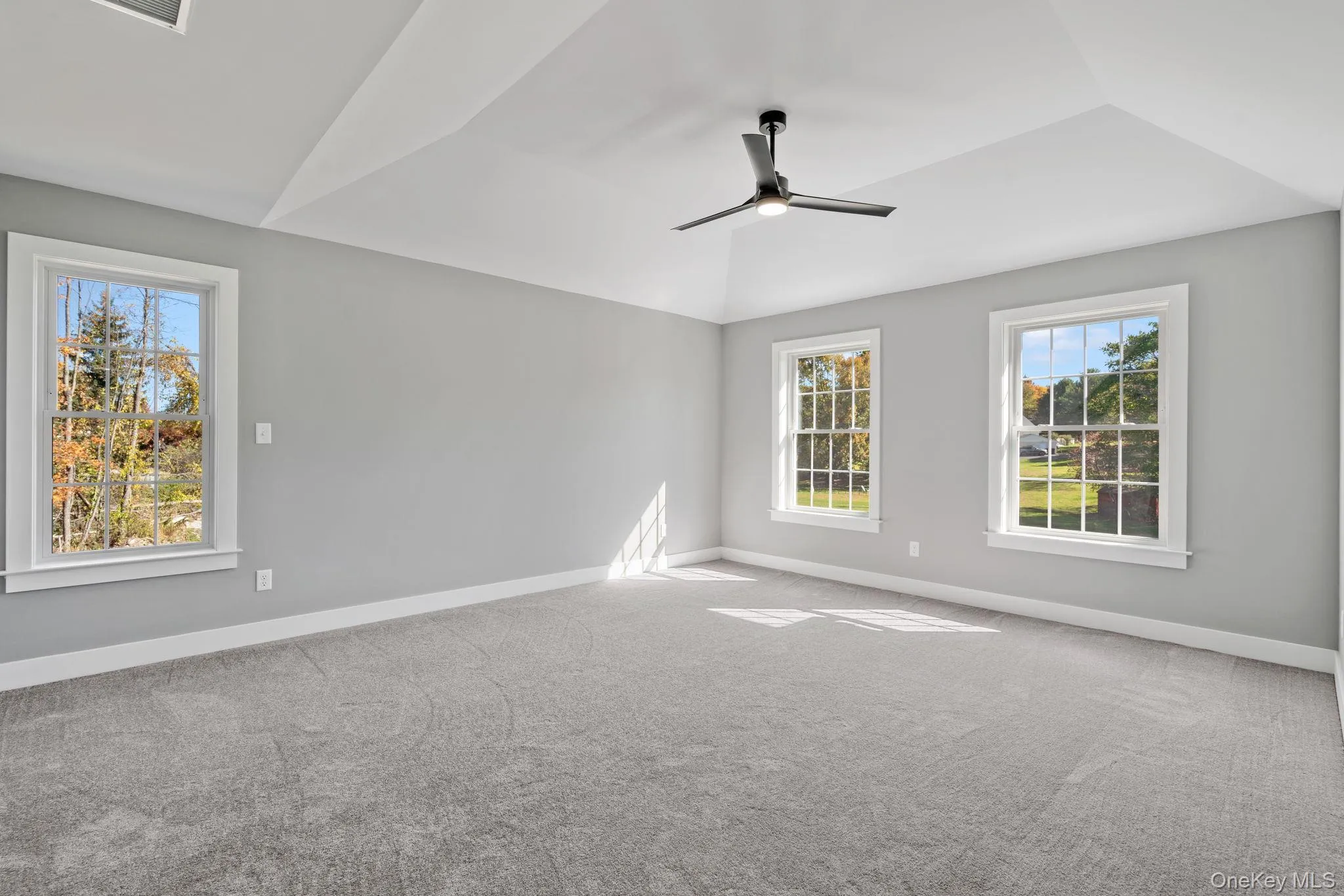 Carpeted empty room featuring baseboards, a ceiling fan, and lofted ceiling Carpeted empty room featuring baseboards, a ceiling fan, and lofted ceiling