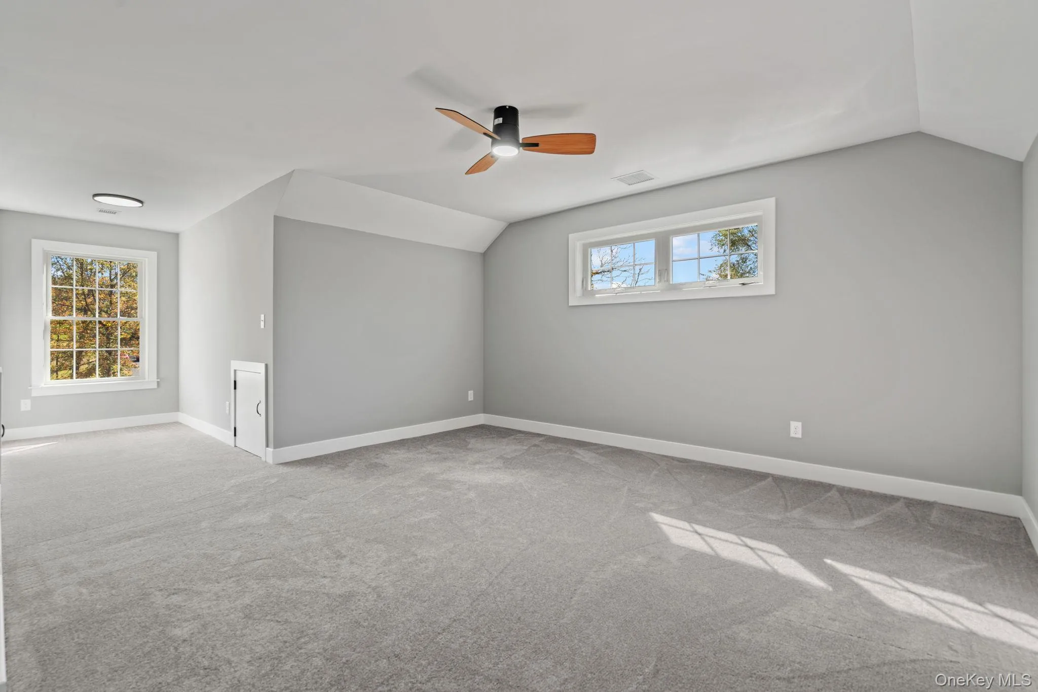 Carpeted spare room featuring ceiling fan, baseboards, visible vents, and lofted ceiling Carpeted spare room featuring ceiling fan, baseboards, visible vents, and lofted ceiling