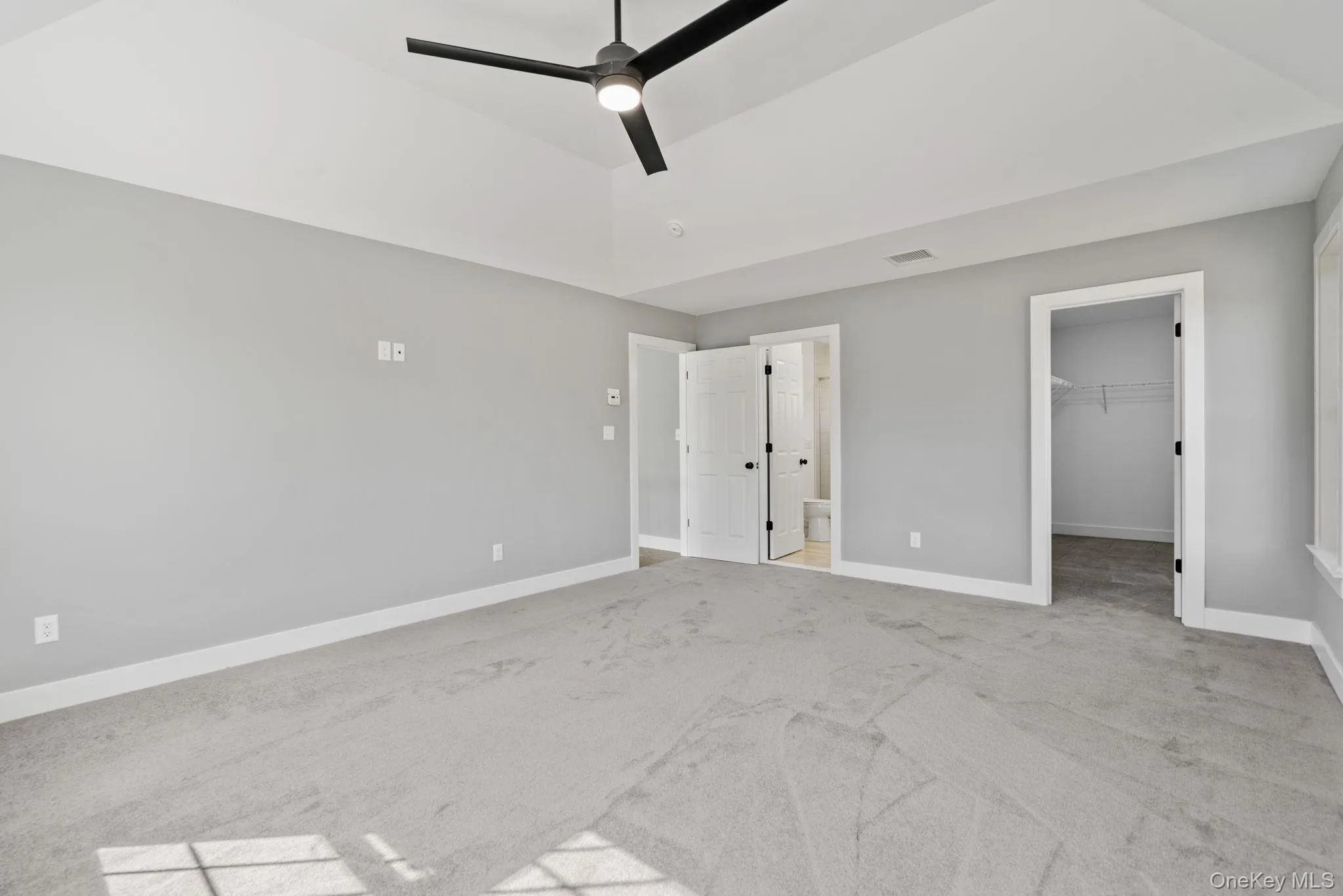 Unfurnished bedroom with carpet flooring, baseboards, a spacious closet, and visible vents Unfurnished bedroom with carpet flooring, baseboards, a spacious closet, and visible vents
