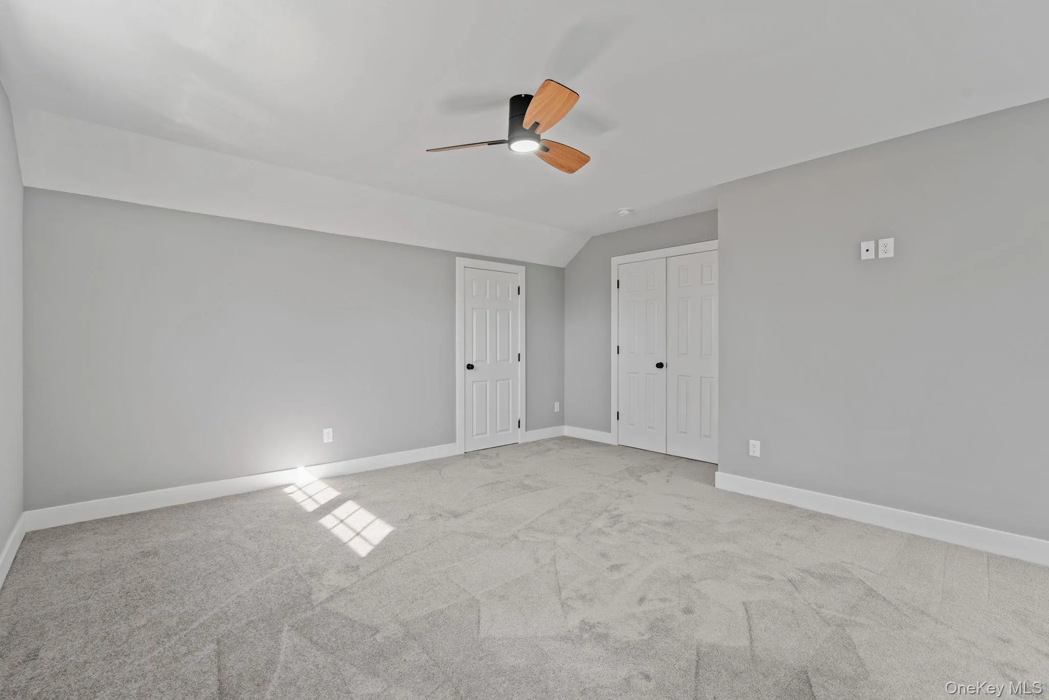 Unfurnished bedroom with baseboards, carpet, and lofted ceiling Unfurnished bedroom with baseboards, carpet, and lofted ceiling