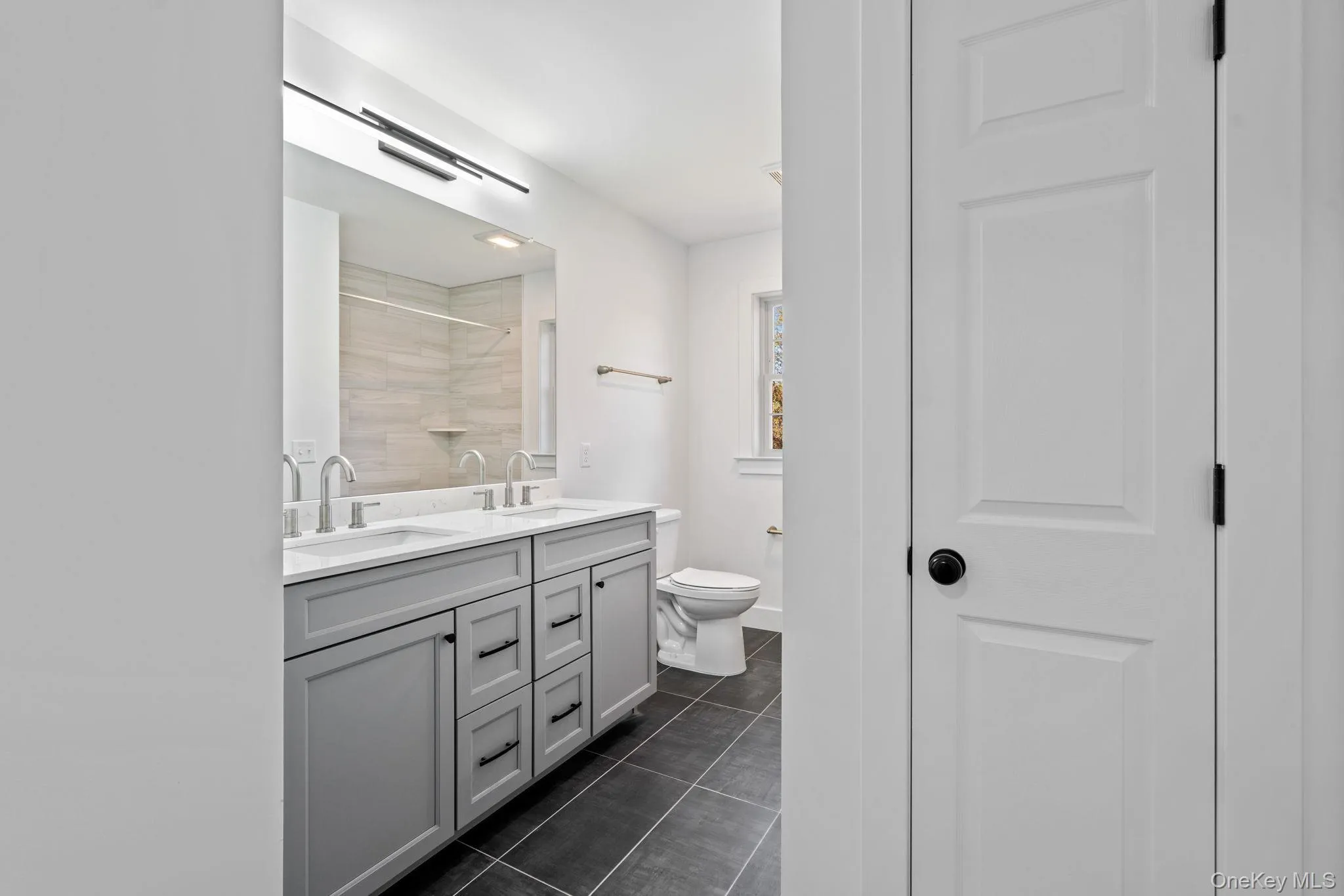 Full bathroom featuring toilet, double vanity, a sink, and tile patterned flooring Full bathroom featuring toilet, double vanity, a sink, and tile patterned flooring