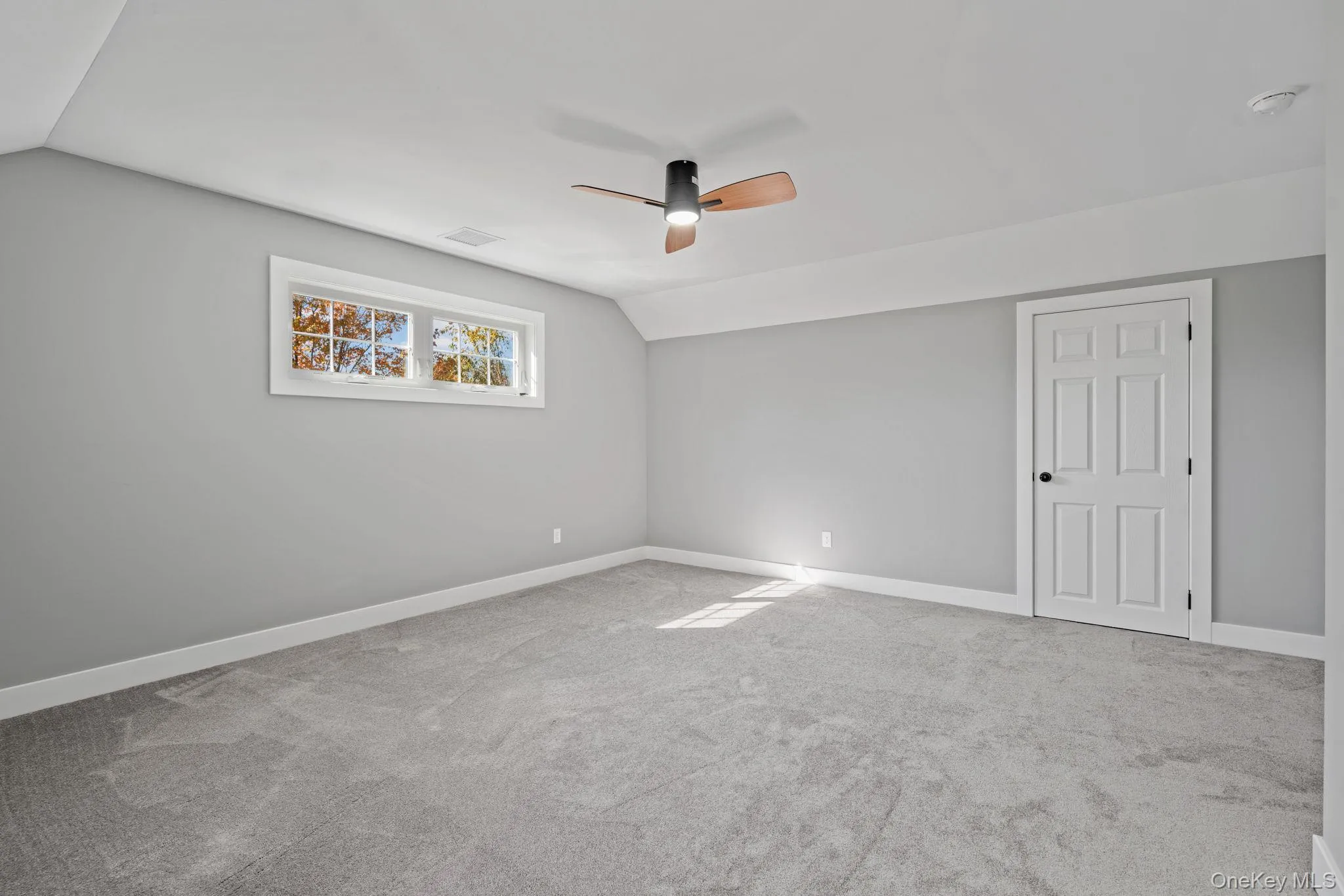 Empty room with baseboards, carpet floors, a ceiling fan, and lofted ceiling Empty room with baseboards, carpet floors, a ceiling fan, and lofted ceiling