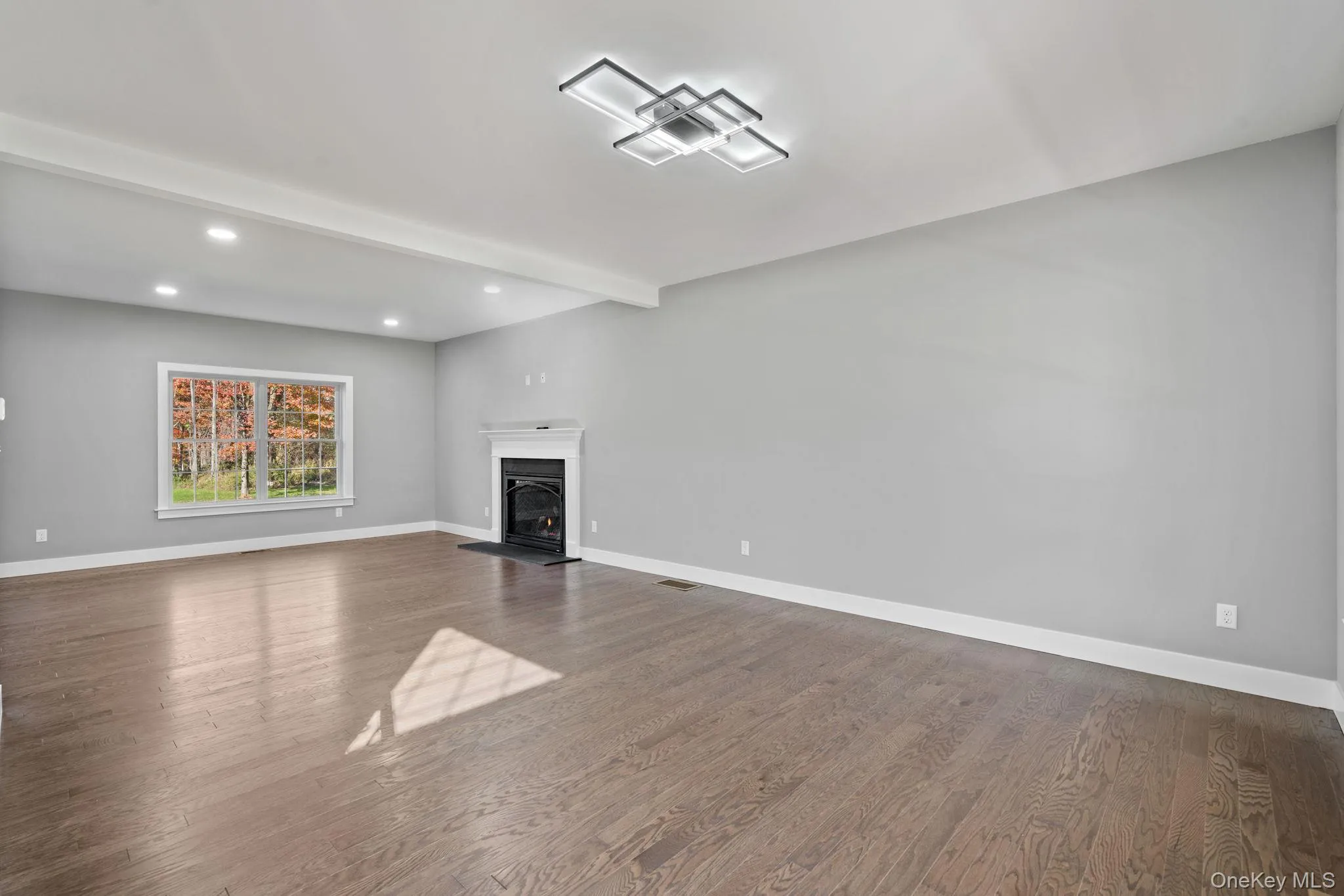 Unfurnished living room with a lit fireplace, visible vents, recessed lighting, dark wood-style flooring, and baseboards Unfurnished living room with a lit fireplace, visible vents, recessed lighting, dark wood-style flooring, and baseboards