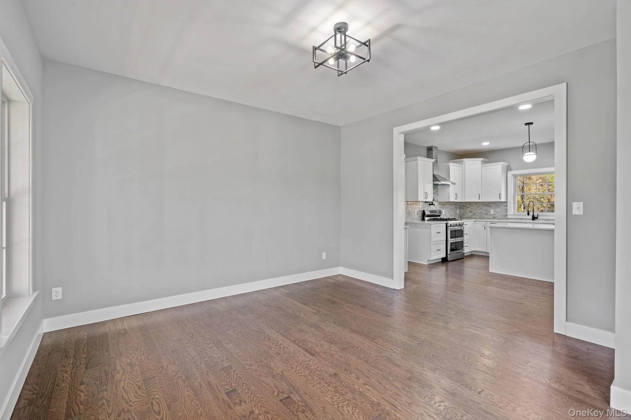 Unfurnished living room with dark wood-type flooring, baseboards, and recessed lighting Unfurnished living room with dark wood-type flooring, baseboards, and recessed lighting