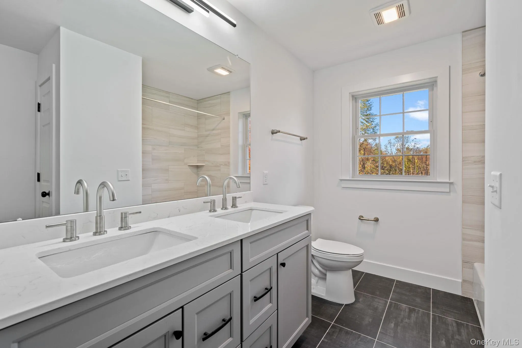 Full bath featuring tiled shower, visible vents, a sink, and toilet Full bath featuring tiled shower, visible vents, a sink, and toilet