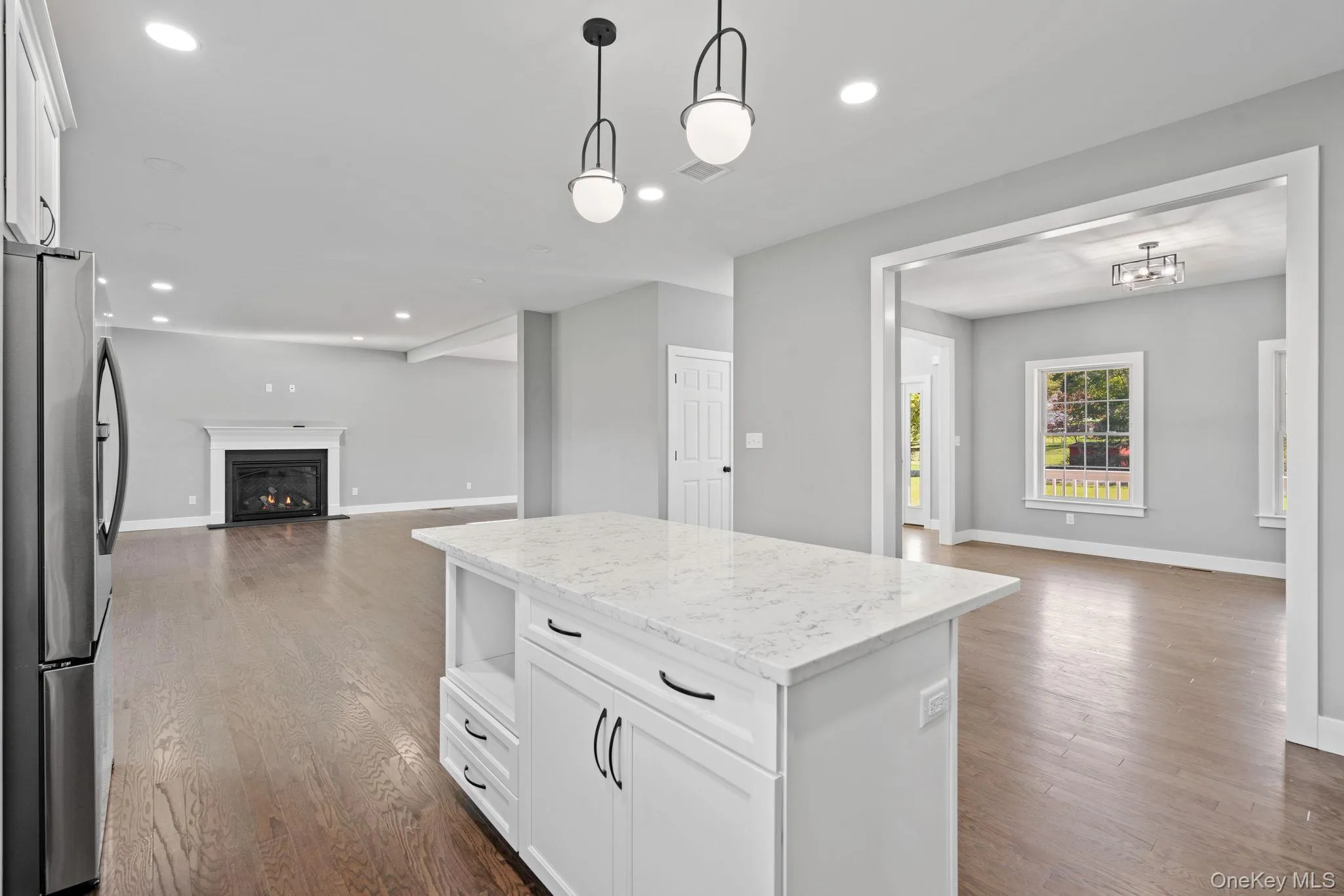 Kitchen featuring dark wood-style flooring, open floor plan, white cabinets, and freestanding refrigerator Kitchen featuring dark wood-style flooring, open floor plan, white cabinets, and freestanding refrigerator