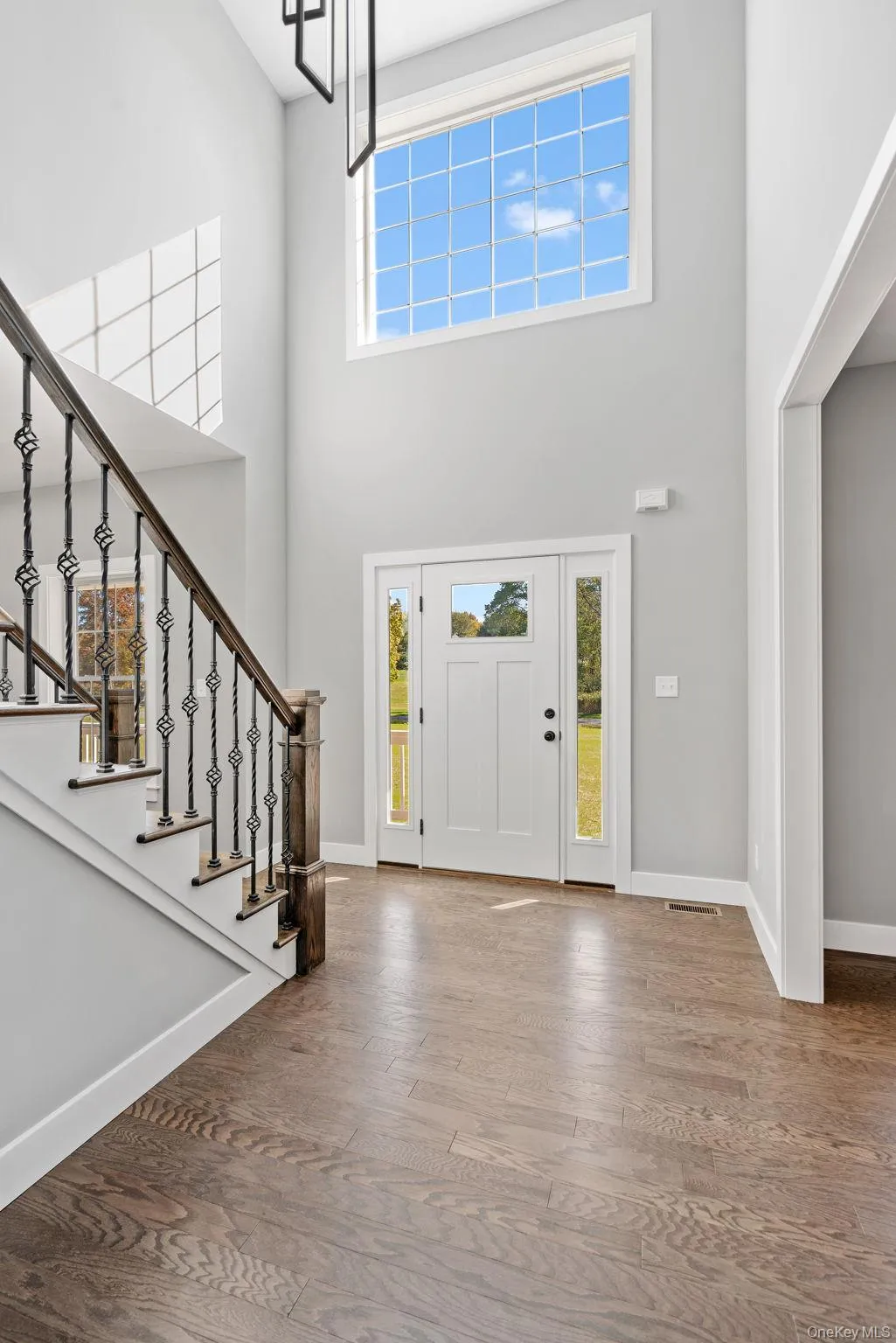 Entryway featuring wood finished floors, a towering ceiling, and stairs Entryway featuring wood finished floors, a towering ceiling, and stairs