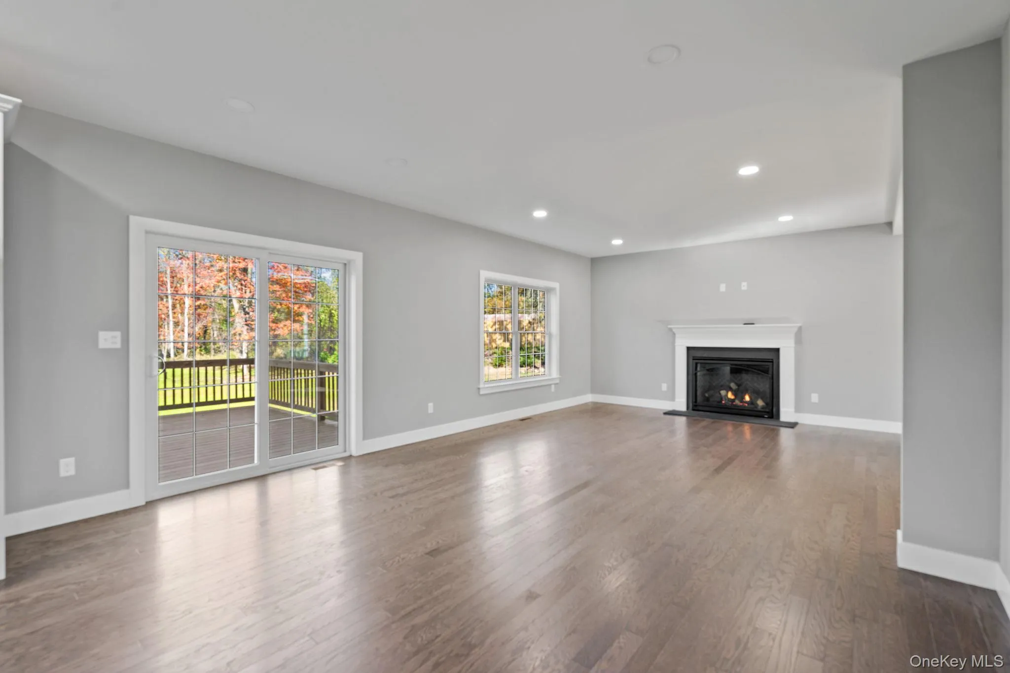 Unfurnished living room featuring wood finished floors, baseboards, a glass covered fireplace, and recessed lighting Unfurnished living room featuring wood finished floors, baseboards, a glass covered fireplace, and recessed lighting