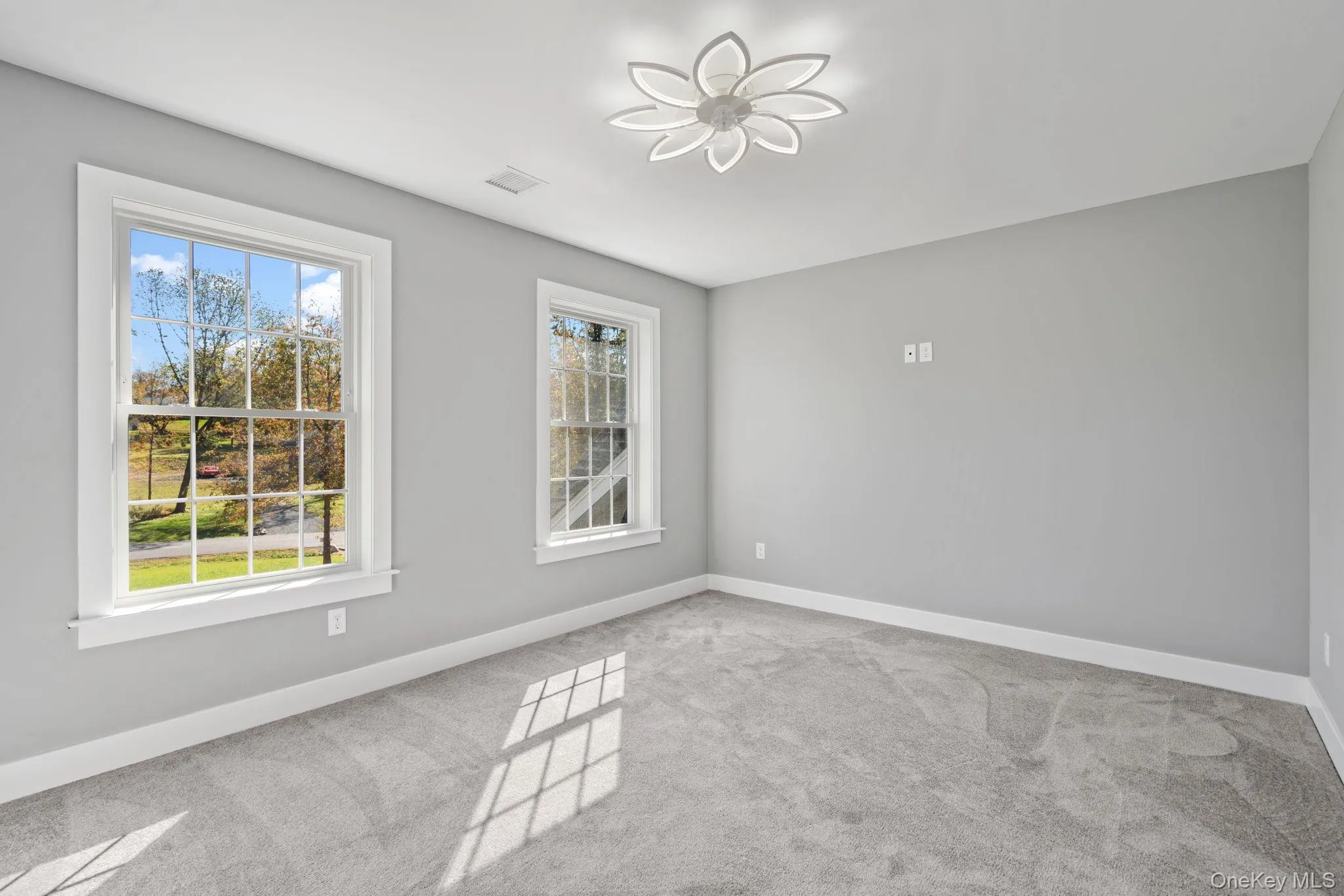 Empty room featuring visible vents, baseboards, carpet, and plenty of natural light Empty room featuring visible vents, baseboards, carpet, and plenty of natural light