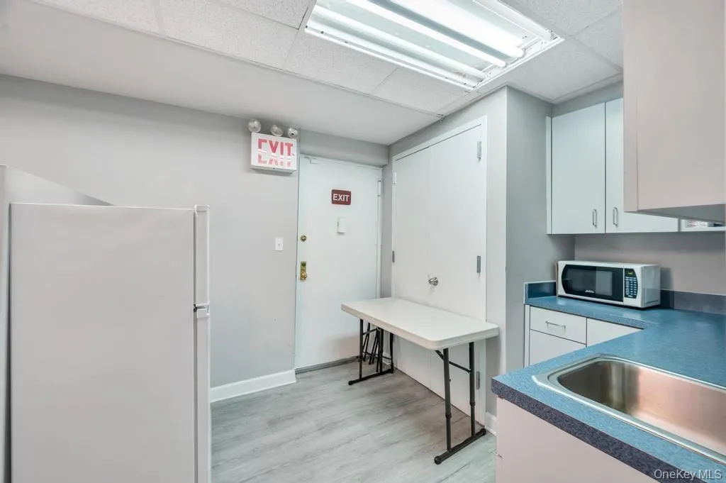 Functional kitchen area featuring a stainless steel sink, light cabinetry, and light wood-finish flooring Functional kitchen area featuring a stainless steel sink, light cabinetry, and light wood-finish flooring