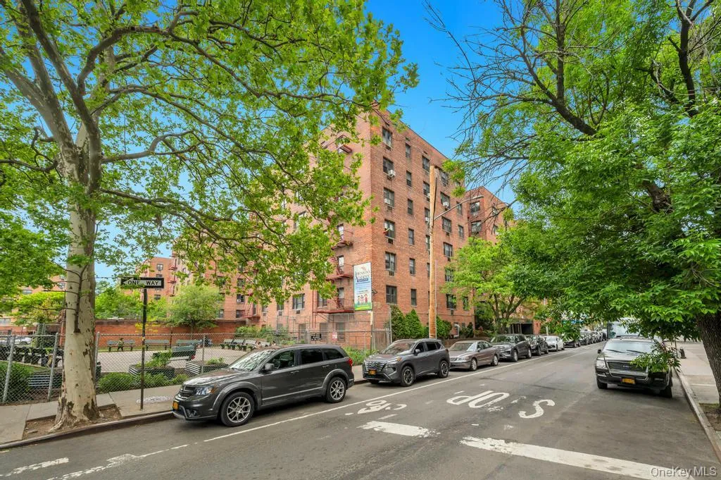 Brick multi-story residential building with multiple windows, featuring mature trees and street parking Brick multi-story residential building with multiple windows, featuring mature trees and street parking