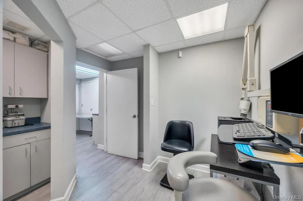 Professional workspace featuring light gray walls, wood-finish flooring, and a suspended ceiling with integrated lighting Professional workspace featuring light gray walls, wood-finish flooring, and a suspended ceiling with integrated lighting