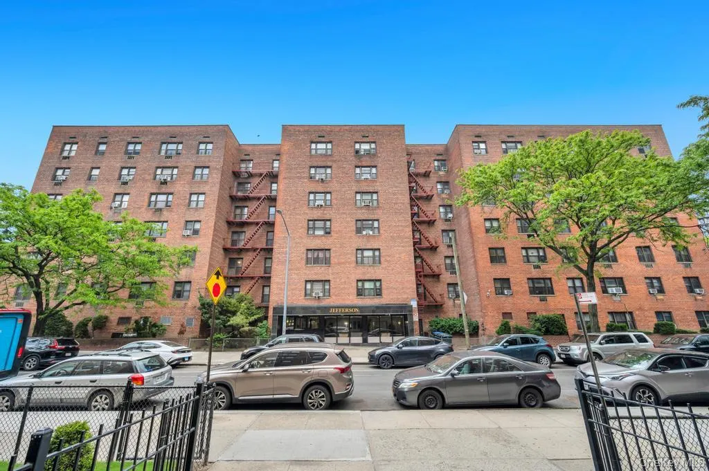Multi-story brick building facade with multiple windows, street-level entrance, and visible fire escapes Multi-story brick building facade with multiple windows, street-level entrance, and visible fire escapes