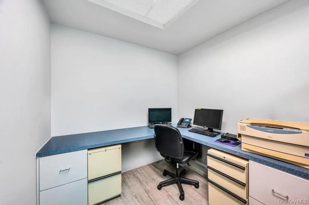 Corner workspace with a light blue speckled countertop, recessed ceiling lighting, and wood-finish flooring Corner workspace with a light blue speckled countertop, recessed ceiling lighting, and wood-finish flooring