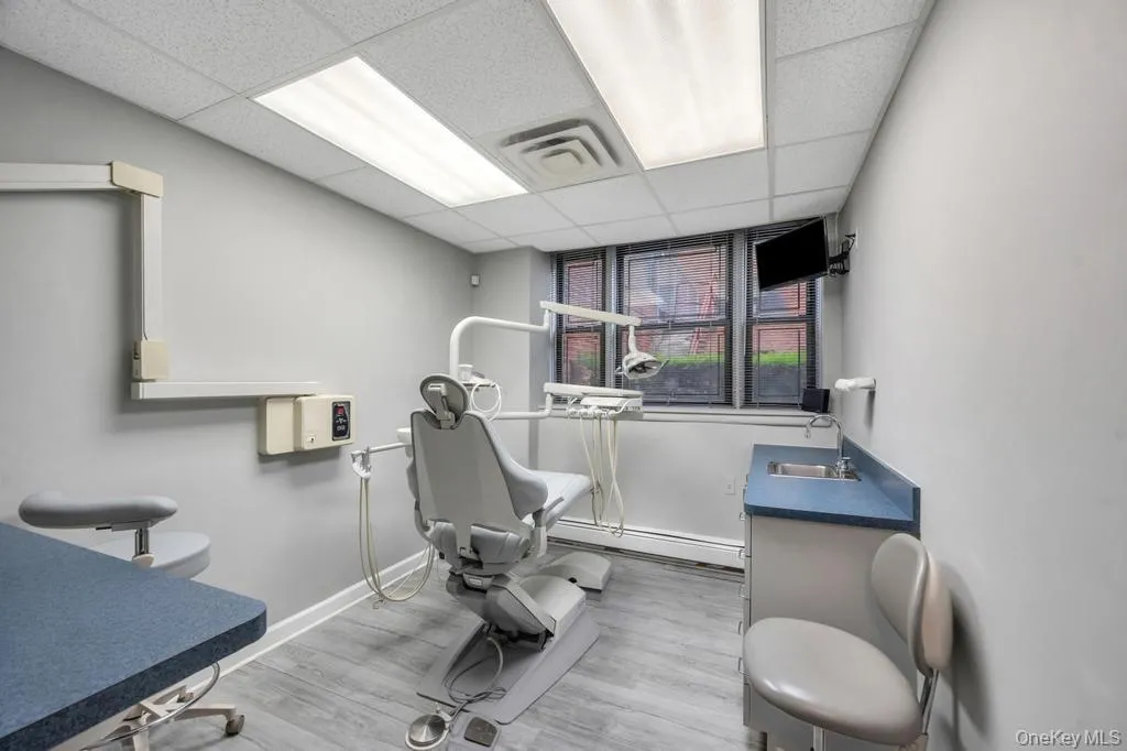 Dedicated clinical space featuring wood-finish flooring, light gray wall paint, and a dropped ceiling with integrated fluorescent lighting Dedicated clinical space featuring wood-finish flooring, light gray wall paint, and a dropped ceiling with integrated fluorescent lighting