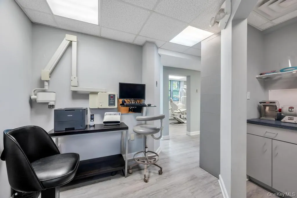 Office space featuring wood-finish flooring, drop ceiling with integrated lighting, and light gray wall paint Office space featuring wood-finish flooring, drop ceiling with integrated lighting, and light gray wall paint