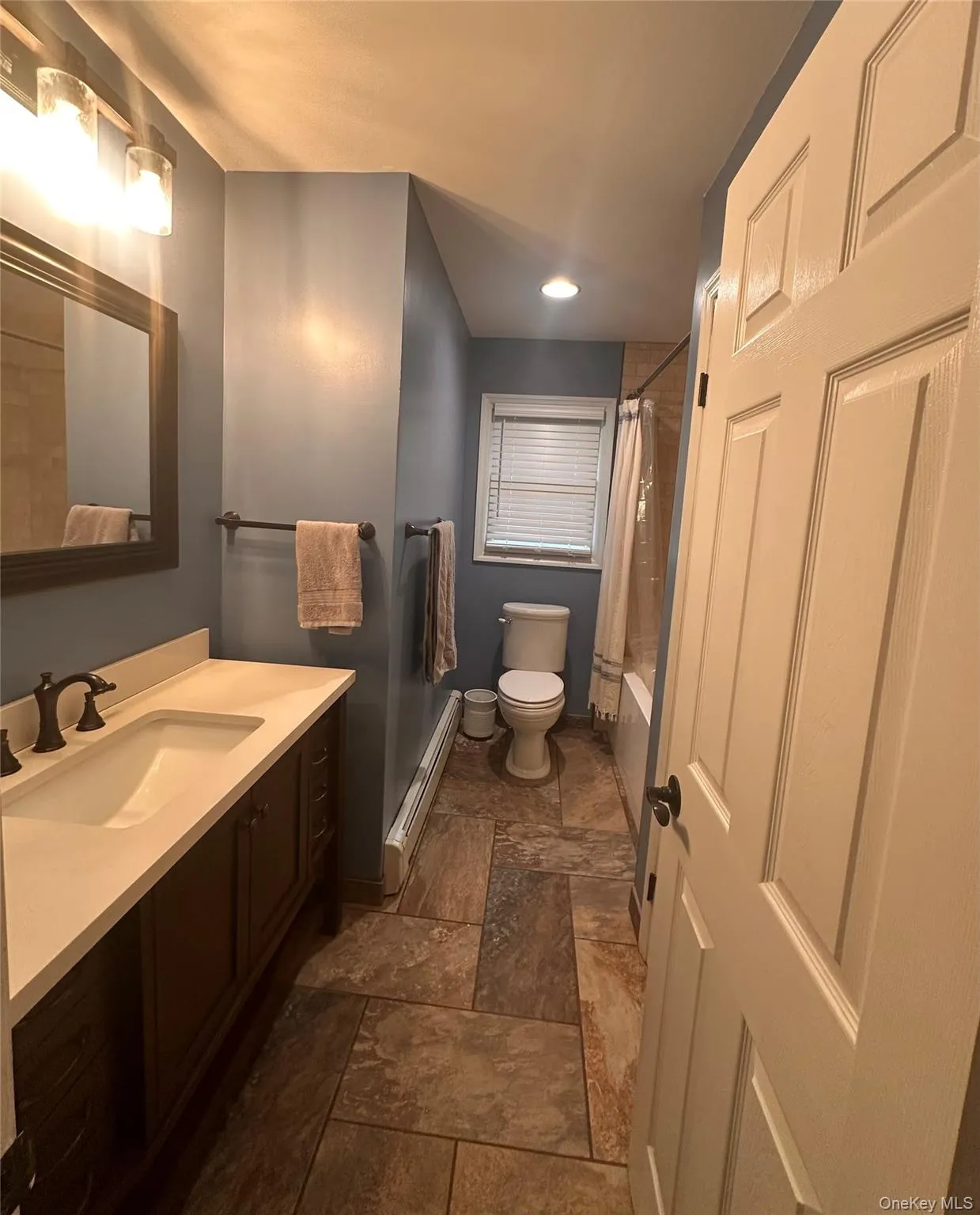 Full bathroom featuring a dark wood-finish vanity with a light-toned countertop, a rectangular undermount sink, and oil-rubbed bronze fixtures Full bathroom featuring a dark wood-finish vanity with a light-toned countertop, a rectangular undermount sink, and oil-rubbed bronze fixtures