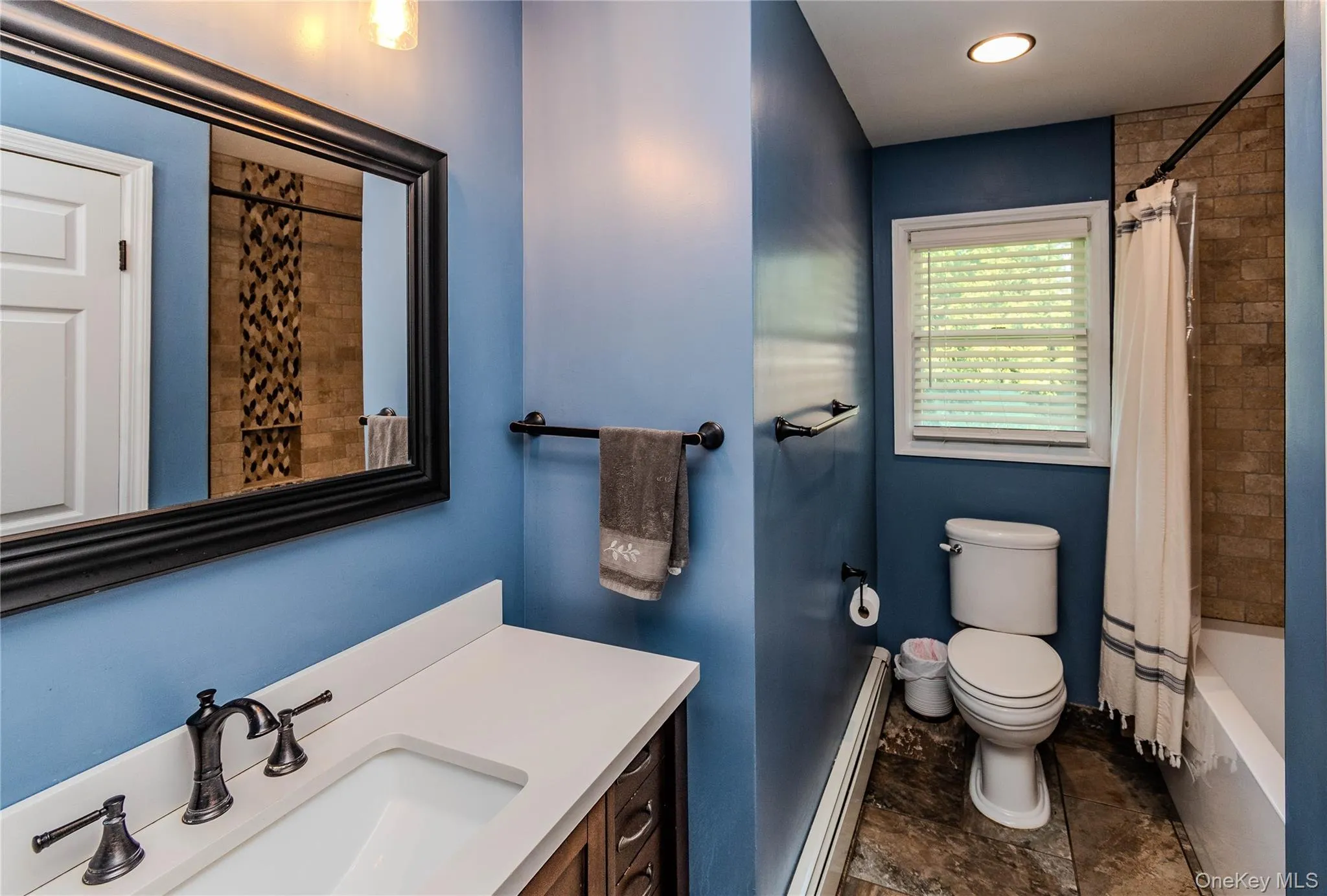 Hall Bathroom featuring a white vanity with a rectangular sink, bronze-finish faucet, and a large framed mirror Hall Bathroom featuring a white vanity with a rectangular sink, bronze-finish faucet, and a large framed mirror