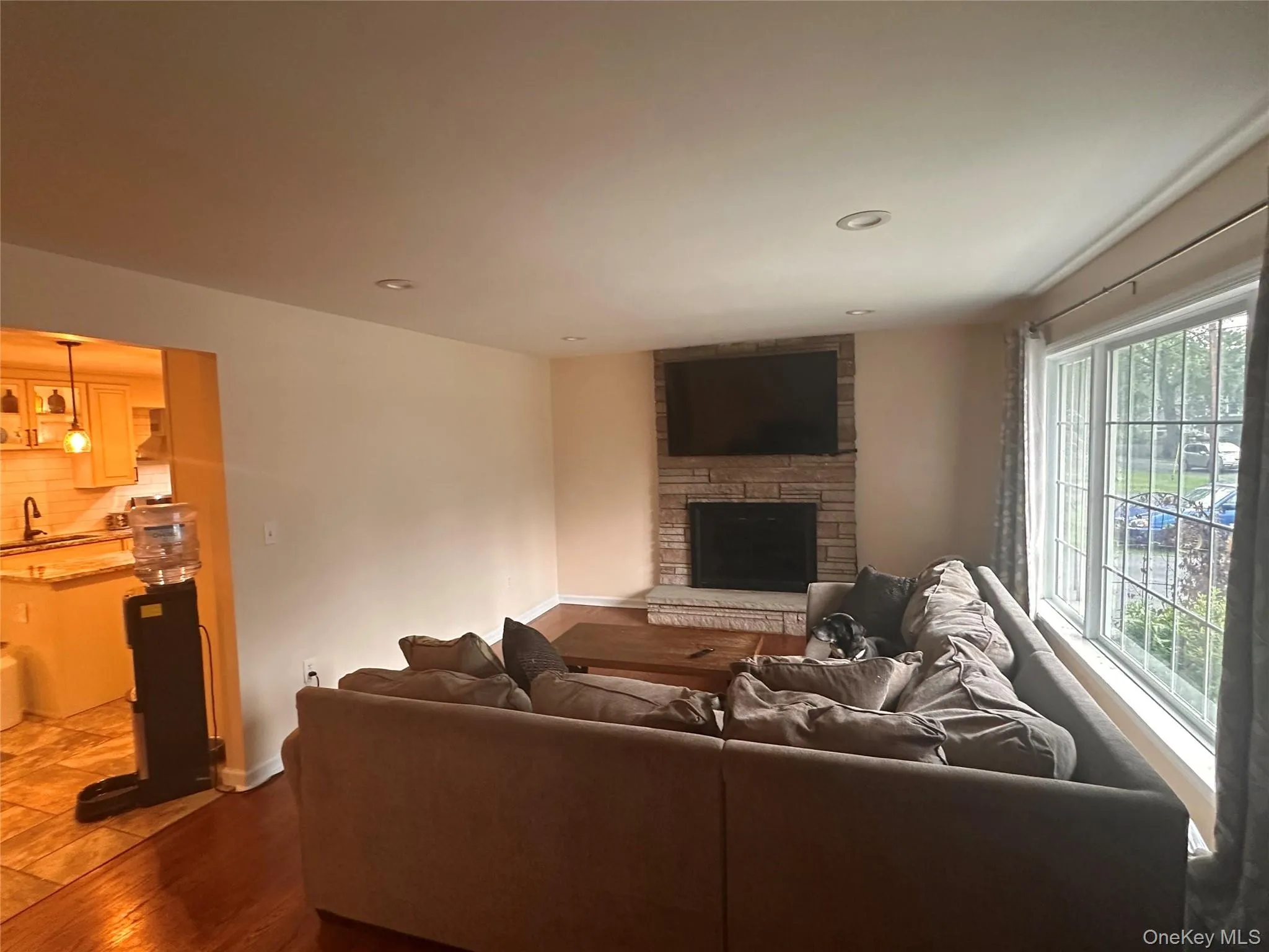 Living area featuring a stone-clad fireplace, large multi-pane windows & hardwood floors Living area featuring a stone-clad fireplace, large multi-pane windows & hardwood floors