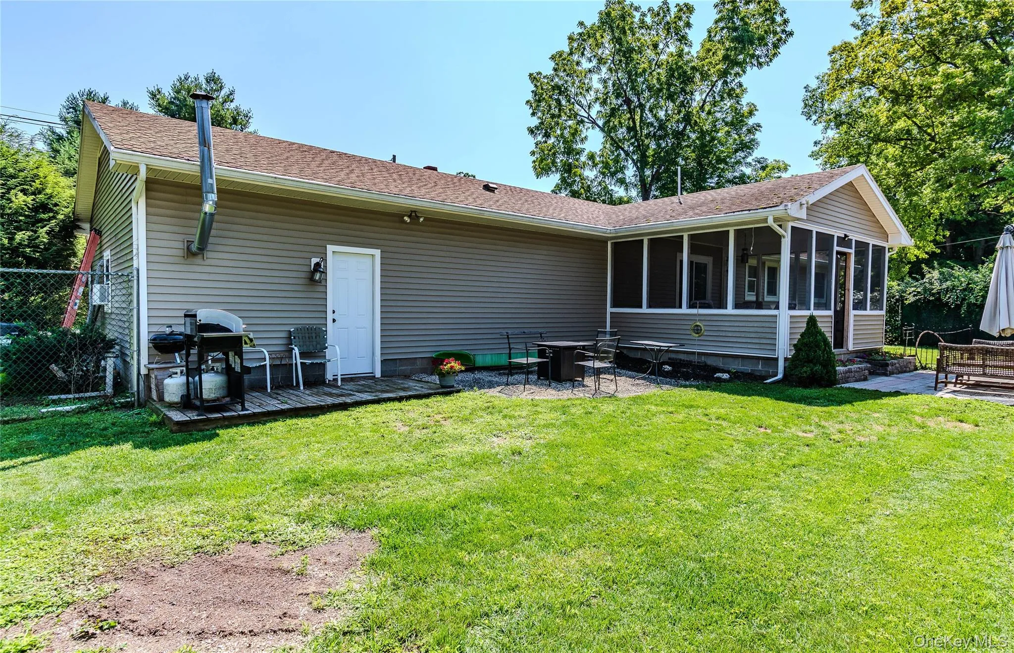 Backyard featuring a screened porch, paver patio, sitting area with fire pit and neutral-toned siding Backyard featuring a screened porch, paver patio, sitting area with fire pit and neutral-toned siding