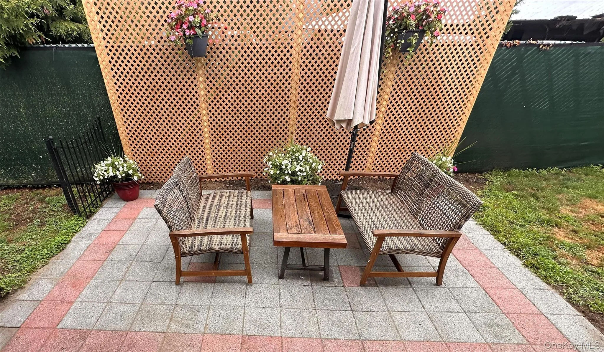 Paved patio with two-tone square tiles, bordered by a decorative lattice screen. Paved patio with two-tone square tiles, bordered by a decorative lattice screen.