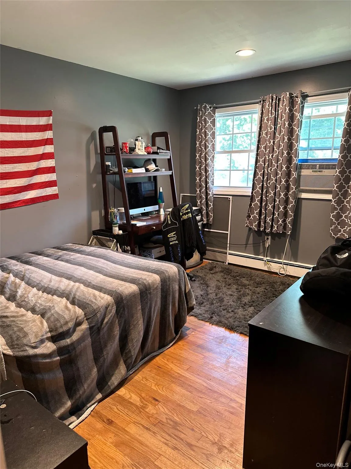 Bedroom 2Room featuring wood-finish flooring, two large windows, a built-in recessed light, and gray-toned walls Bedroom 2Room featuring wood-finish flooring, two large windows, a built-in recessed light, and gray-toned walls