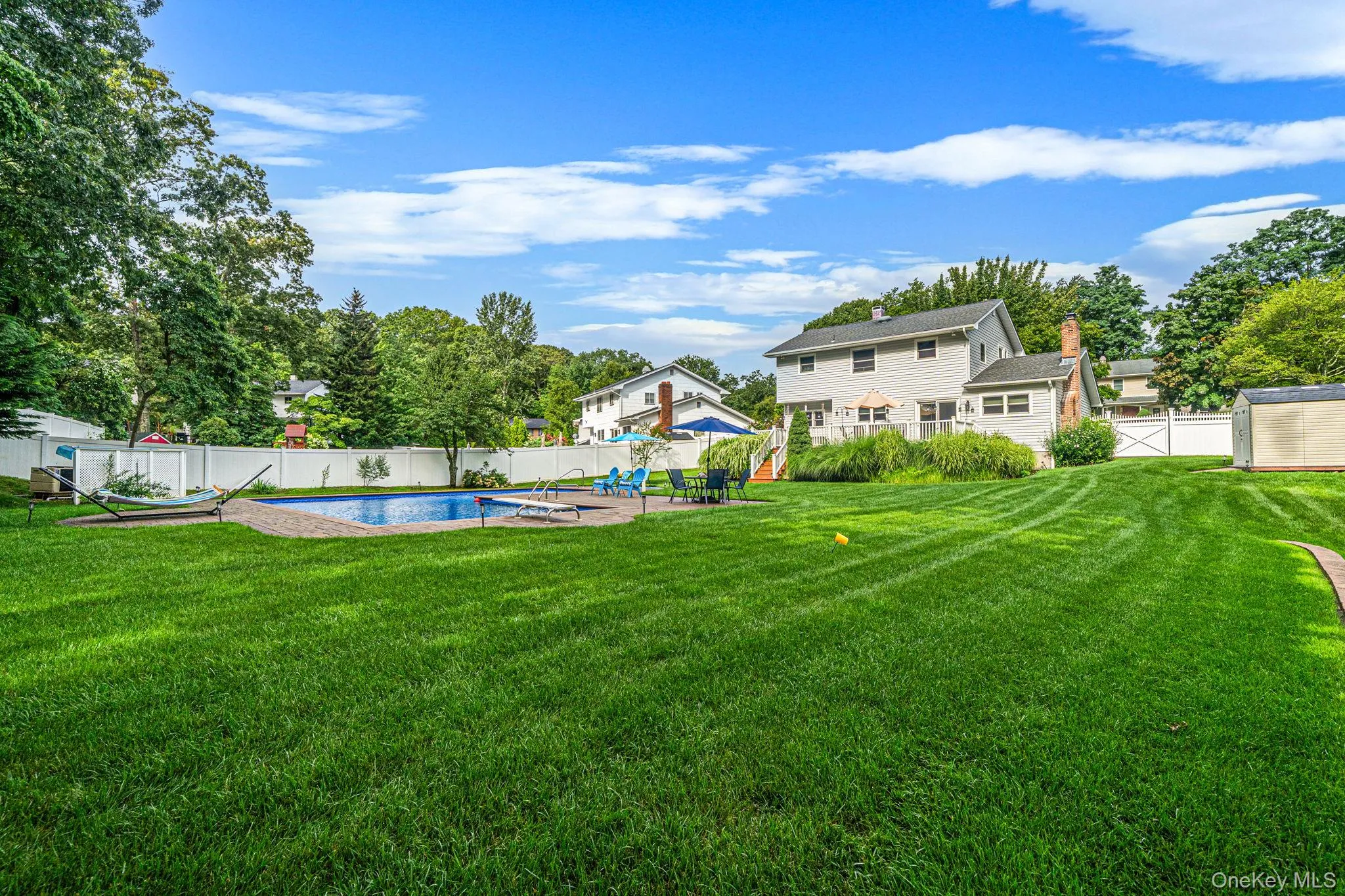 Expansive backyard featuring a large in-ground swimming pool, a substantial lawn area, perimeter fencing, and a detached storage shed Expansive backyard featuring a large in-ground swimming pool, a substantial lawn area, perimeter fencing, and a detached storage shed