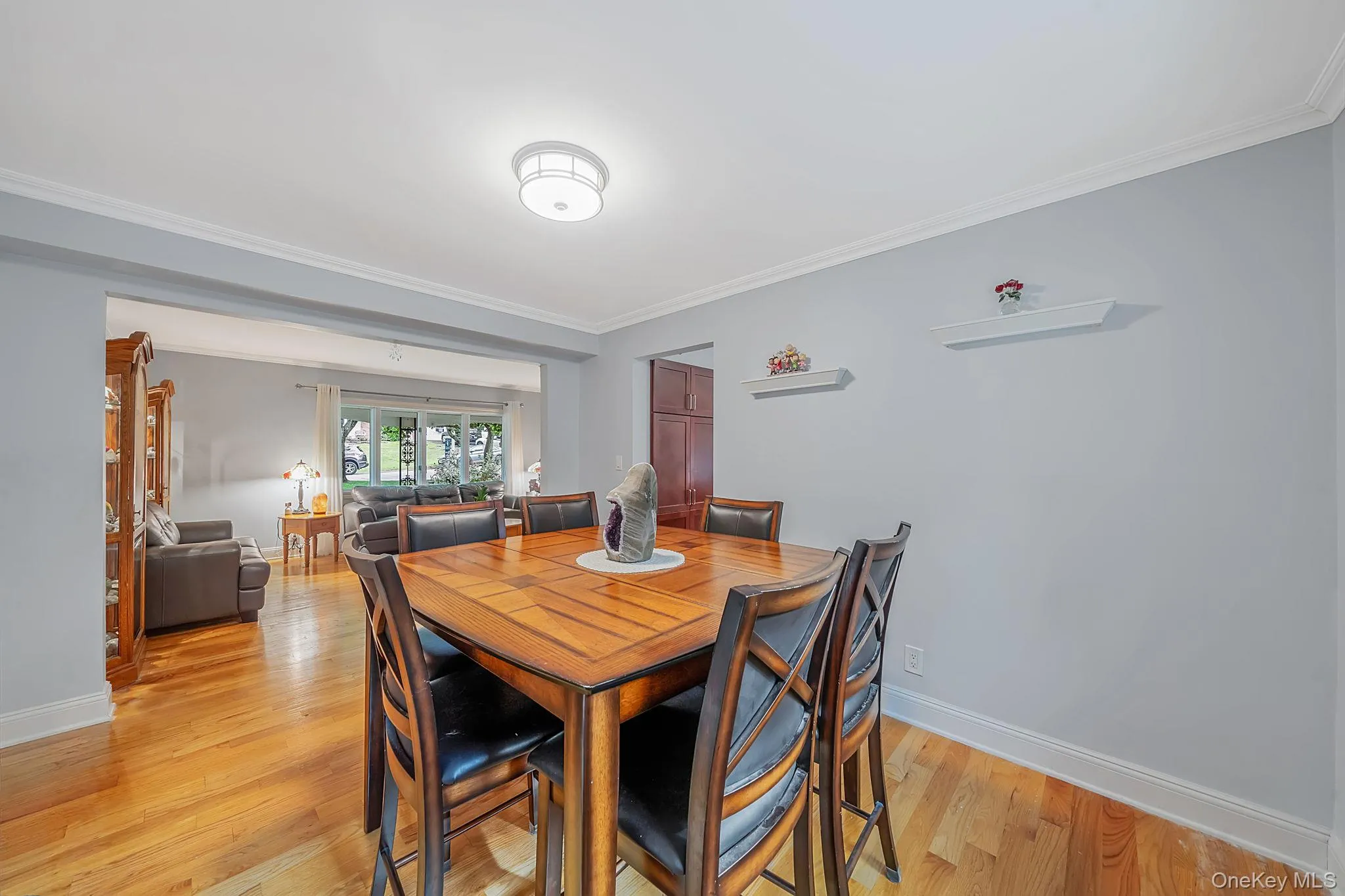 Spacious dining room featuring warm hardwood flooring, light gray wall paint, and white crown molding Spacious dining room featuring warm hardwood flooring, light gray wall paint, and white crown molding