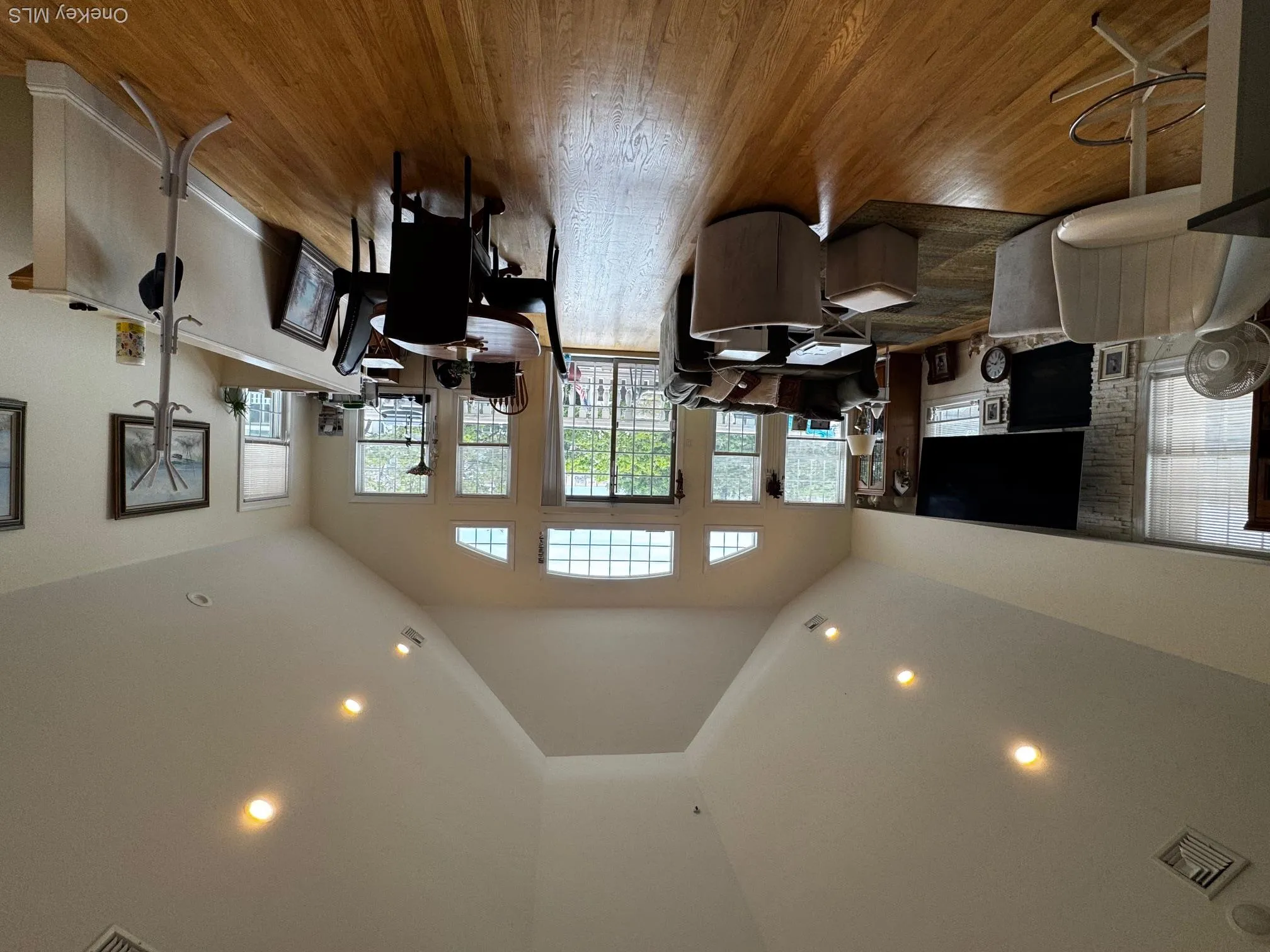 Living room with a stone fireplace, wood finished floors, recessed lighting, and high vaulted ceiling Living room with a stone fireplace, wood finished floors, recessed lighting, and high vaulted ceiling