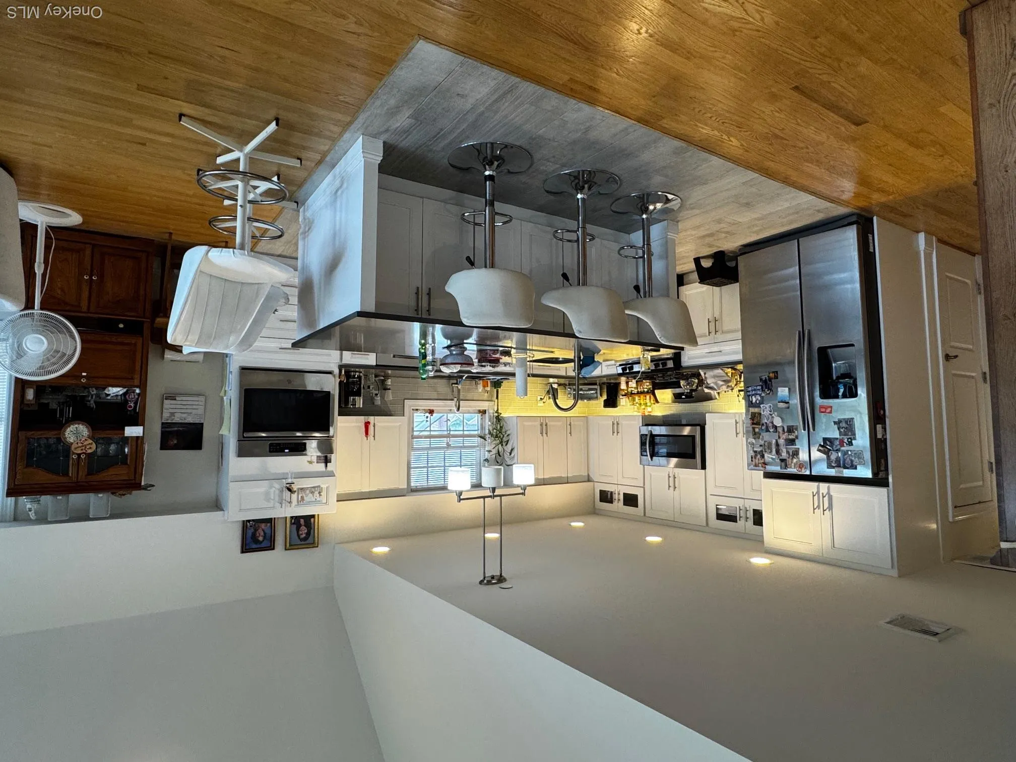 Kitchen with fridge, wall oven, light wood finished floors, dark countertops, and recessed lighting Kitchen with fridge, wall oven, light wood finished floors, dark countertops, and recessed lighting