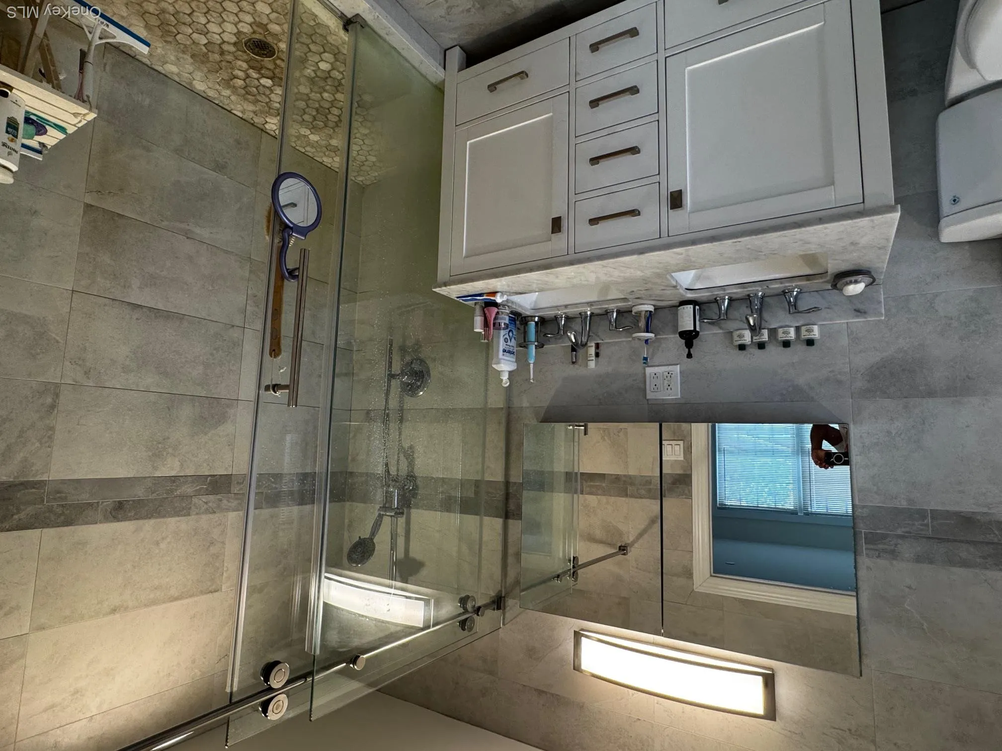 Bathroom with tile walls, double vanity, and a shower stall Bathroom with tile walls, double vanity, and a shower stall